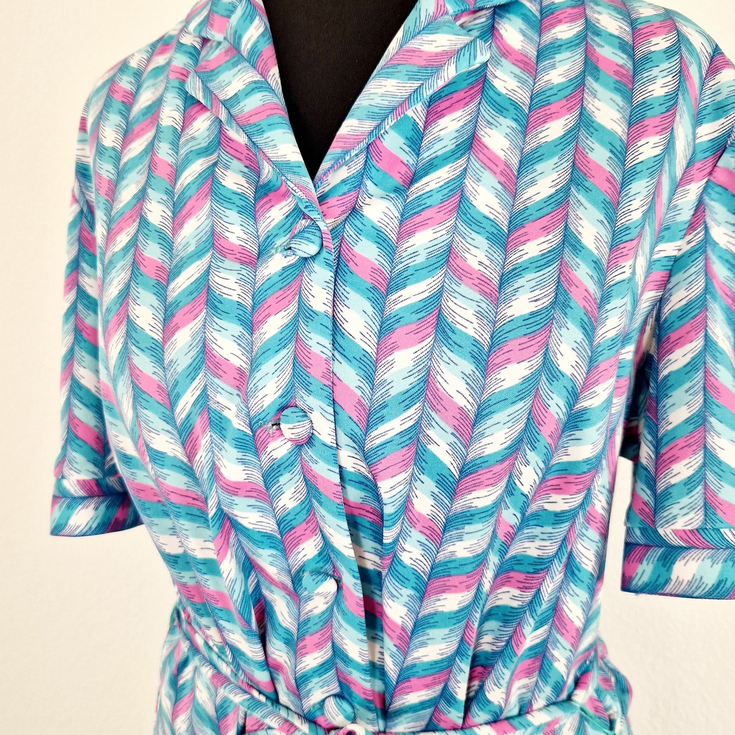 Einzigartiges und nachhaltiges Vintage Kleid, Kurzarm, in türkis-weiss-pink, geometrisch. Unique and sustainable vintage dress, shortsleeved, in turquois-white-pink, geometric. Close-up.