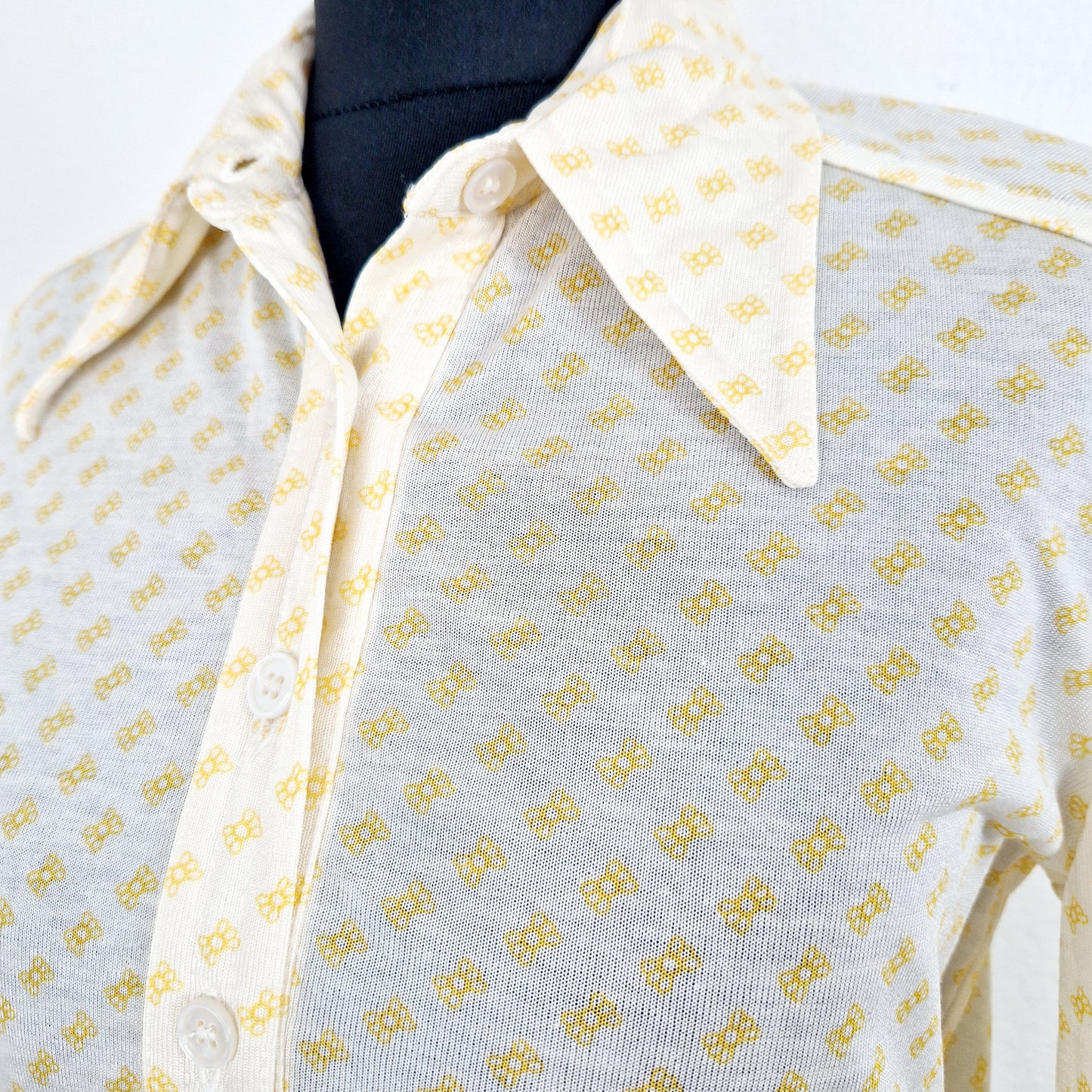 Einzigartige und nachhaltige Vintage Bluse in eierschale-gelb mit Maschen. Unique and sustainable vintage blouse in off-white-yellow with bows. Close-up.