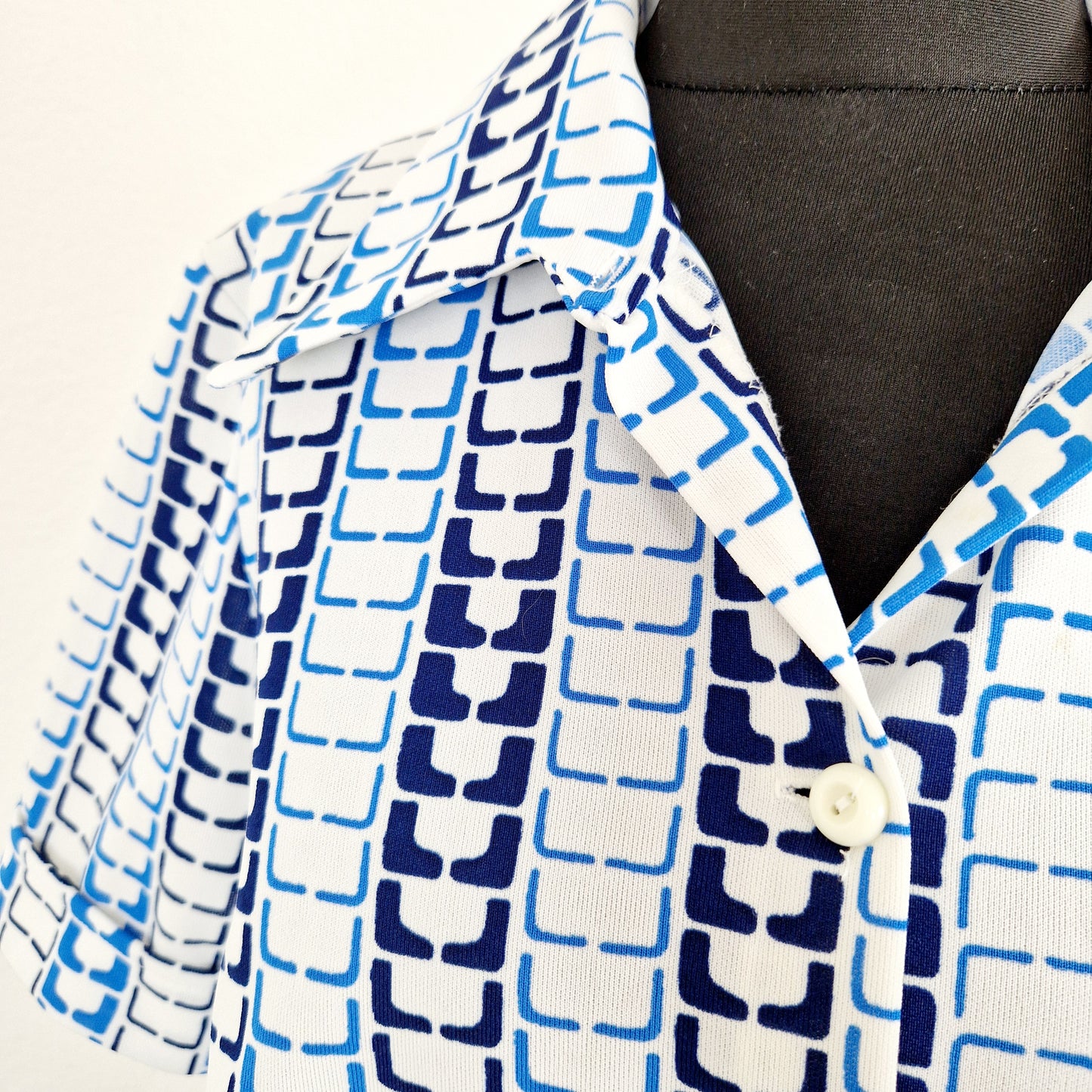 Einzigartie und nachhaltige Vintage Bluse in weiss-blau, geometrisch. Unique and sustainable vintage blouse in white-blue, geometrisch pattern. Close-up.