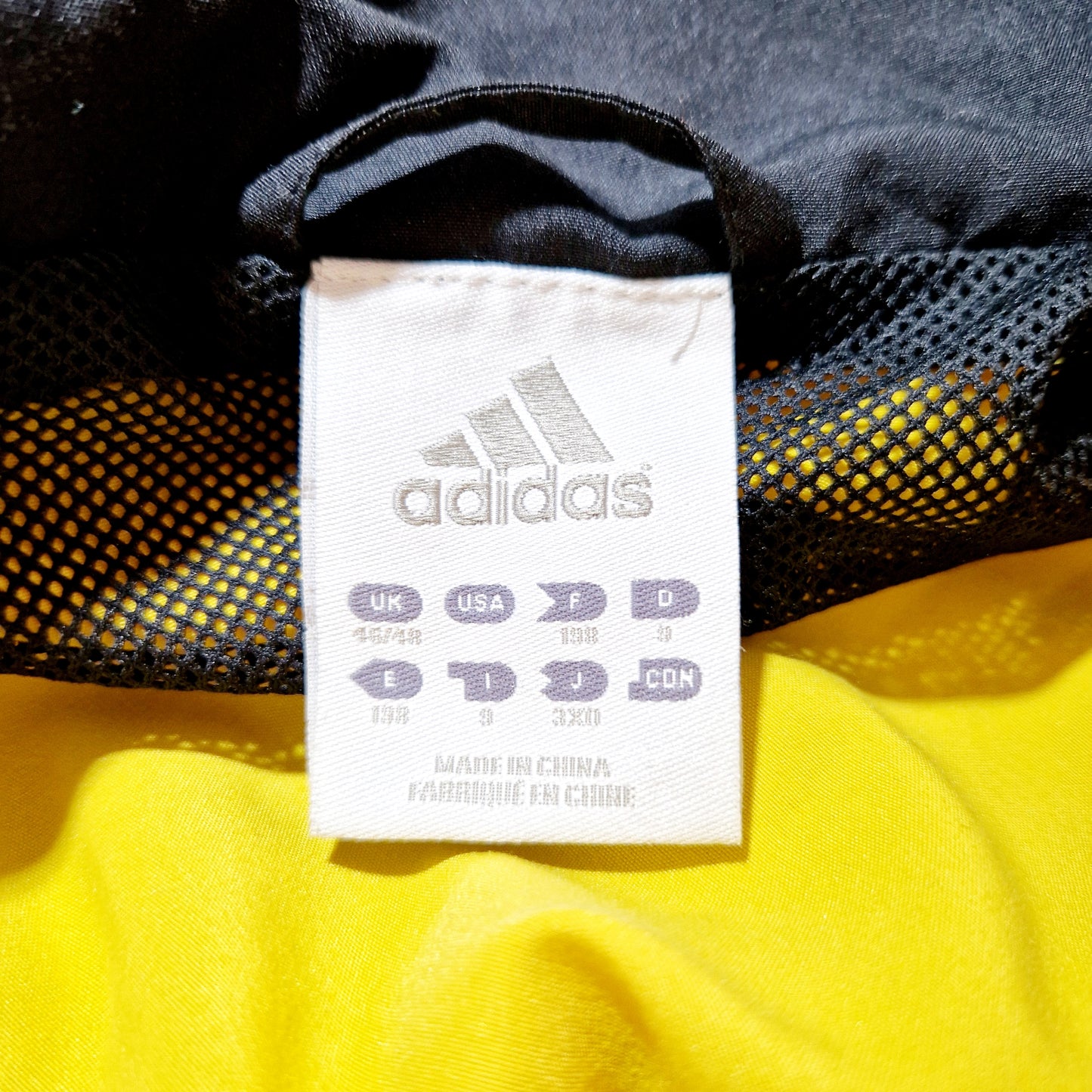 Einzigartige und nachhaltige Vintage Trainerjacke von Adidas in gelb-schwarz. Unique and sustainable vintage track jacket from Adidas in yellow-black. Tag.