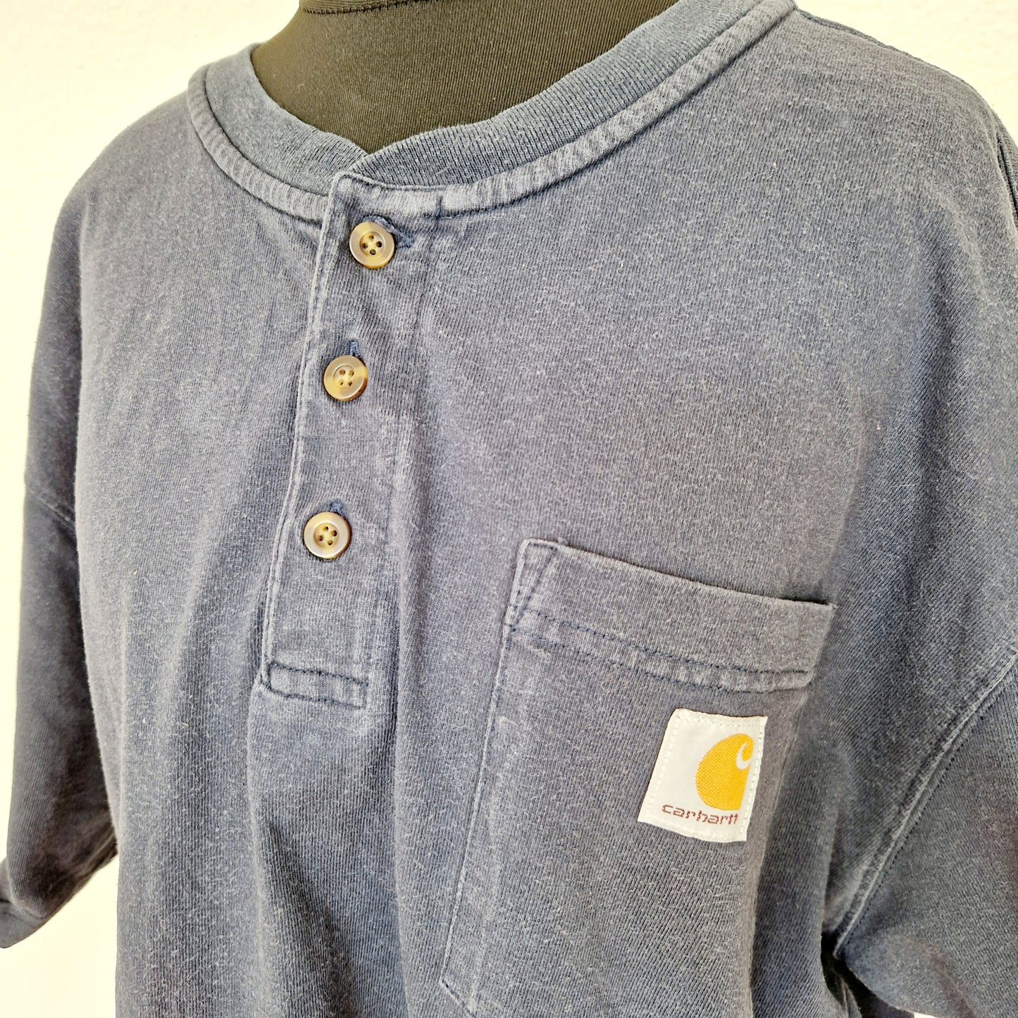 Einzigartiges und nachhaltiges Vintage T-Shirt in dunkelblau mit Knöpfen von Carhartt. Unique and sustainable vintage t-shirt in dark blue with buttons from Carhartt. Close-up.