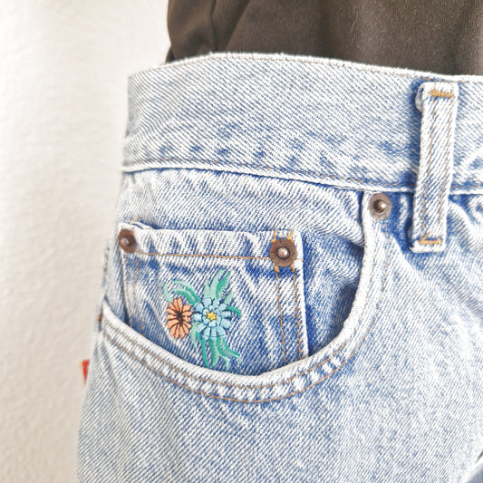 Einzigartige und nachhaltige Vintage Jeans, mittelblau, mit Blumenstickereien. Close-up.