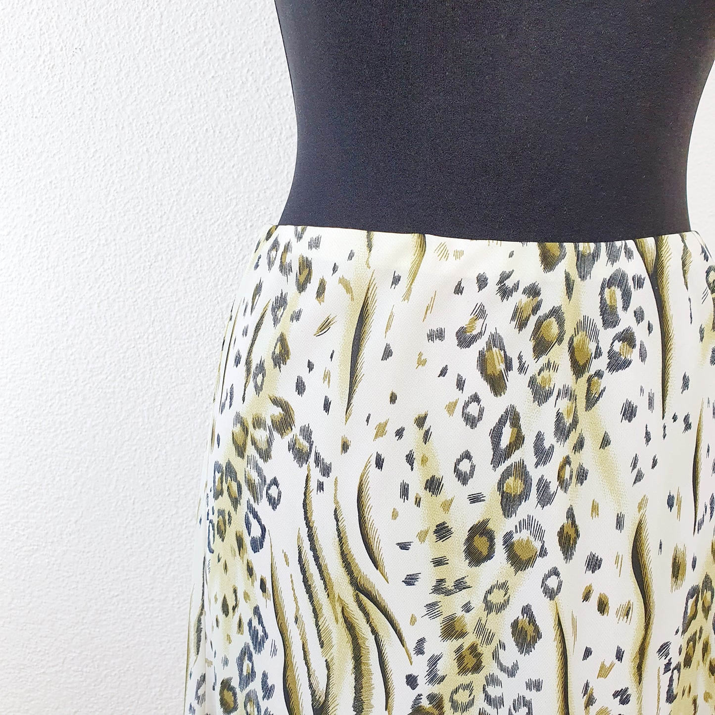 Einzigartiger und nachhaltiger Vintage Rock in oliv-weiss mit Leo-Print. Unique and sustainable vintage skirt in olive-green-white with leo print. Close-up.