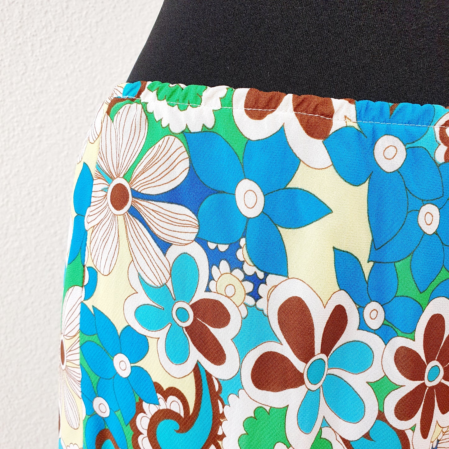 Einzigartiger und nachhaltiger Vintage Rock in türkis-grün-gelb mit Blumen. Unique and sustainable vintage skirt in turquoise-green-yellow with flowers. Close-up.