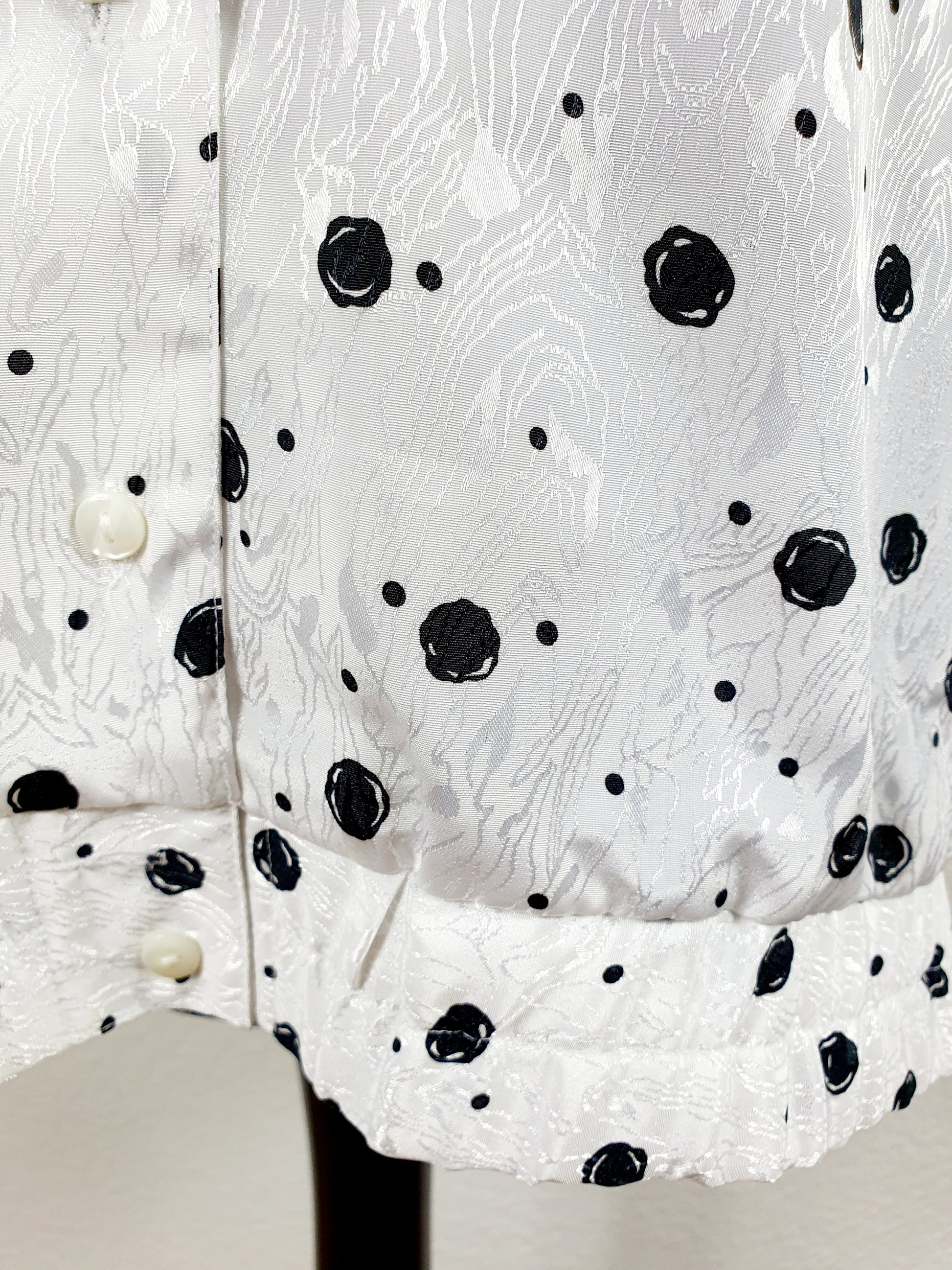 Einzigartige und nachhaltige Vintage Bluse in weiss-schwarz mit Punkten. Unique and sustainable vintage blouse in white-black with polka dots. Close-up.