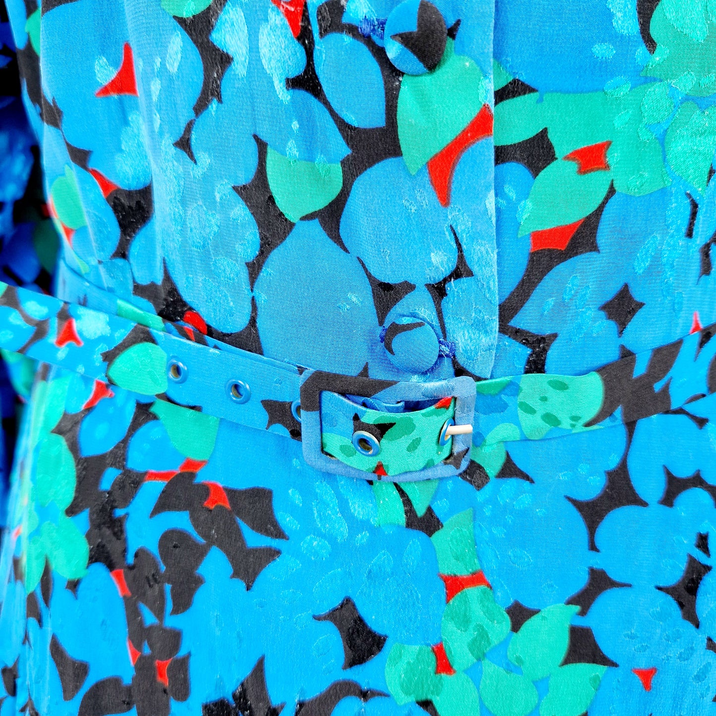 Einzigartiges und nachhaltiges Vintage Kleid in blau-grün-rot mit Blättern. Unique and sustainable vintage dress in blue-green-red with leaves. Close-up.