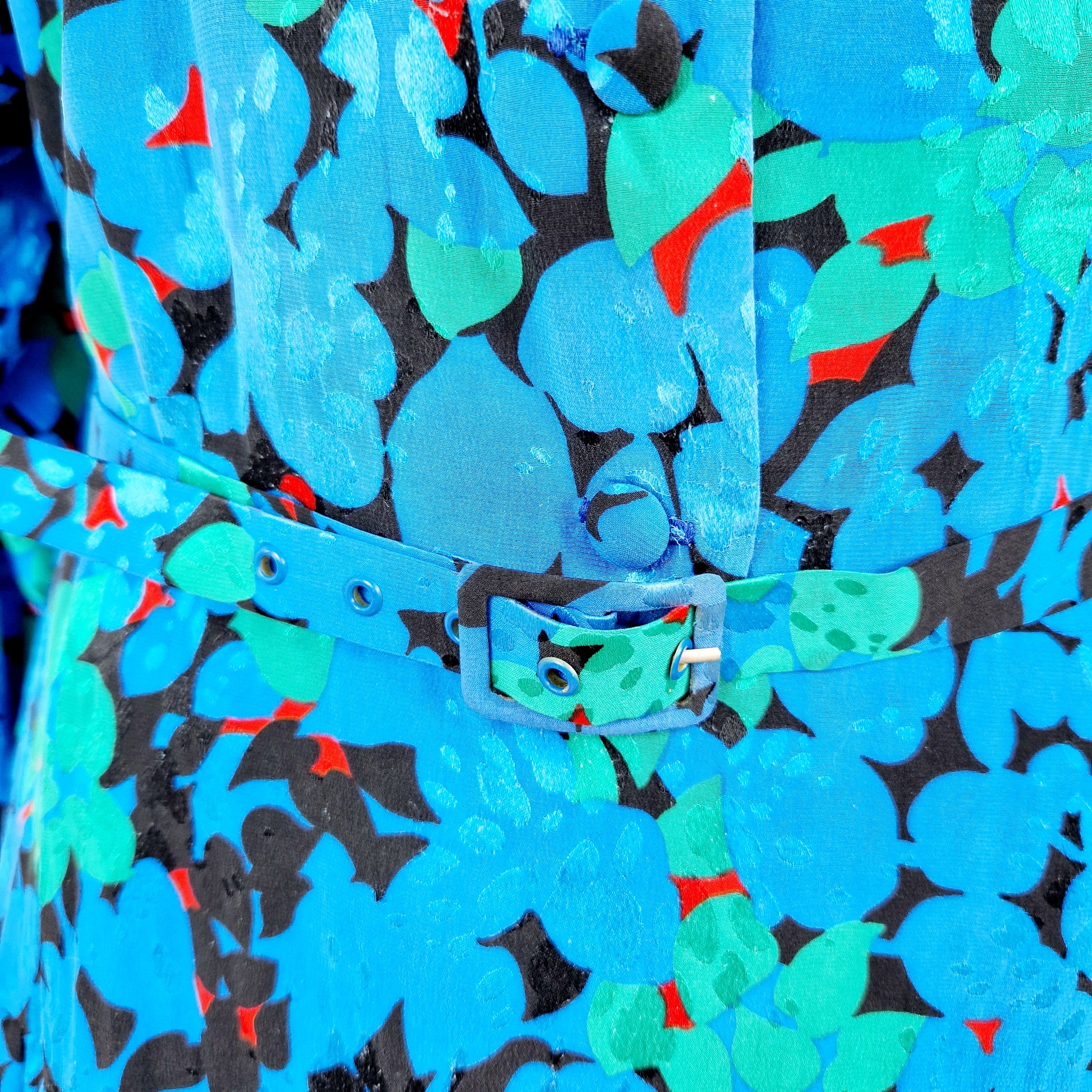Einzigartiges und nachhaltiges Vintage Kleid in blau-grün-rot mit Blättern. Unique and sustainable vintage dress in blue-green-red with leaves. Close-up.