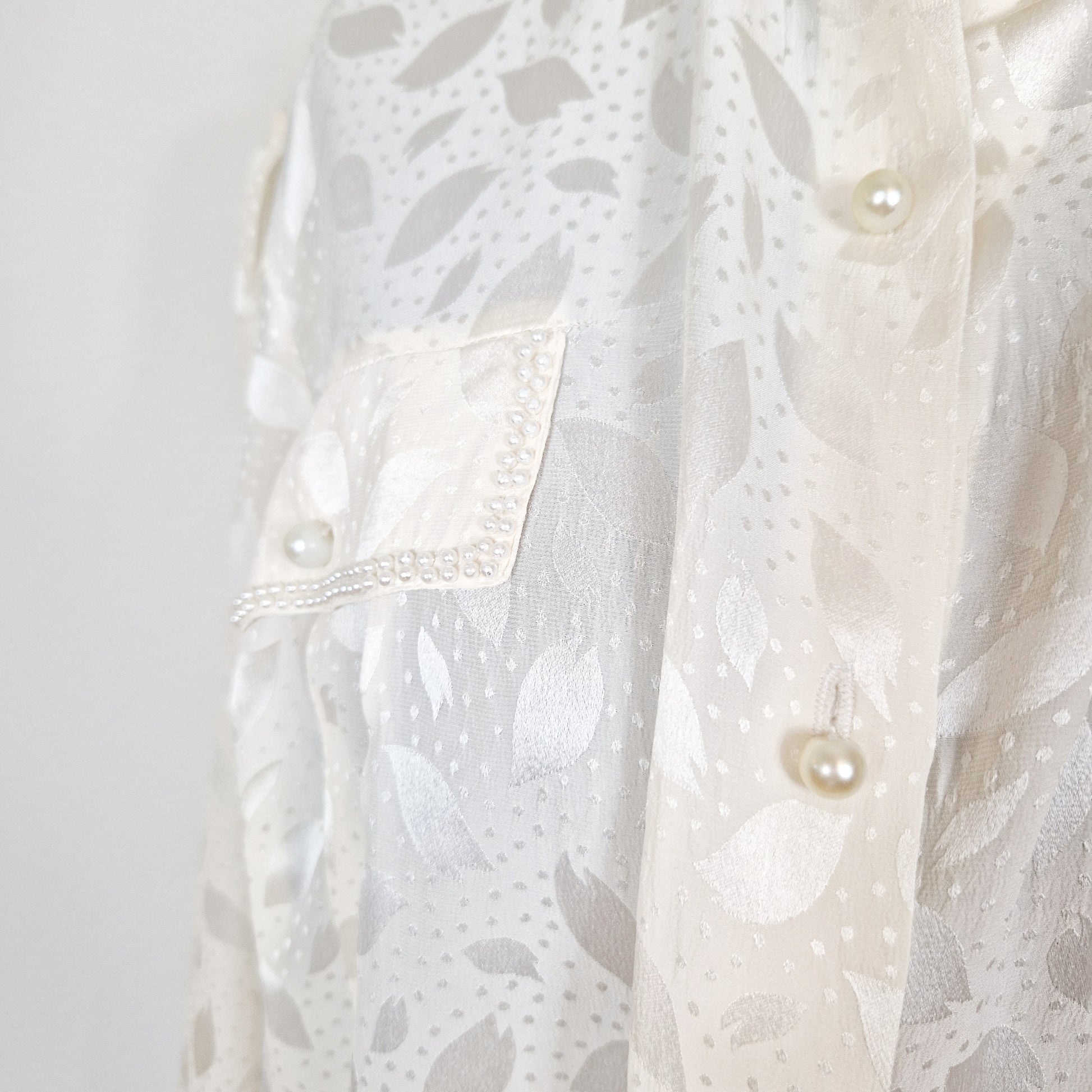 Einzigartige und nachhaltige Vintage Bluse in eierschale mit Perlen. Unique and sustainable vintage blouse in off-white with pearls. Close-up.