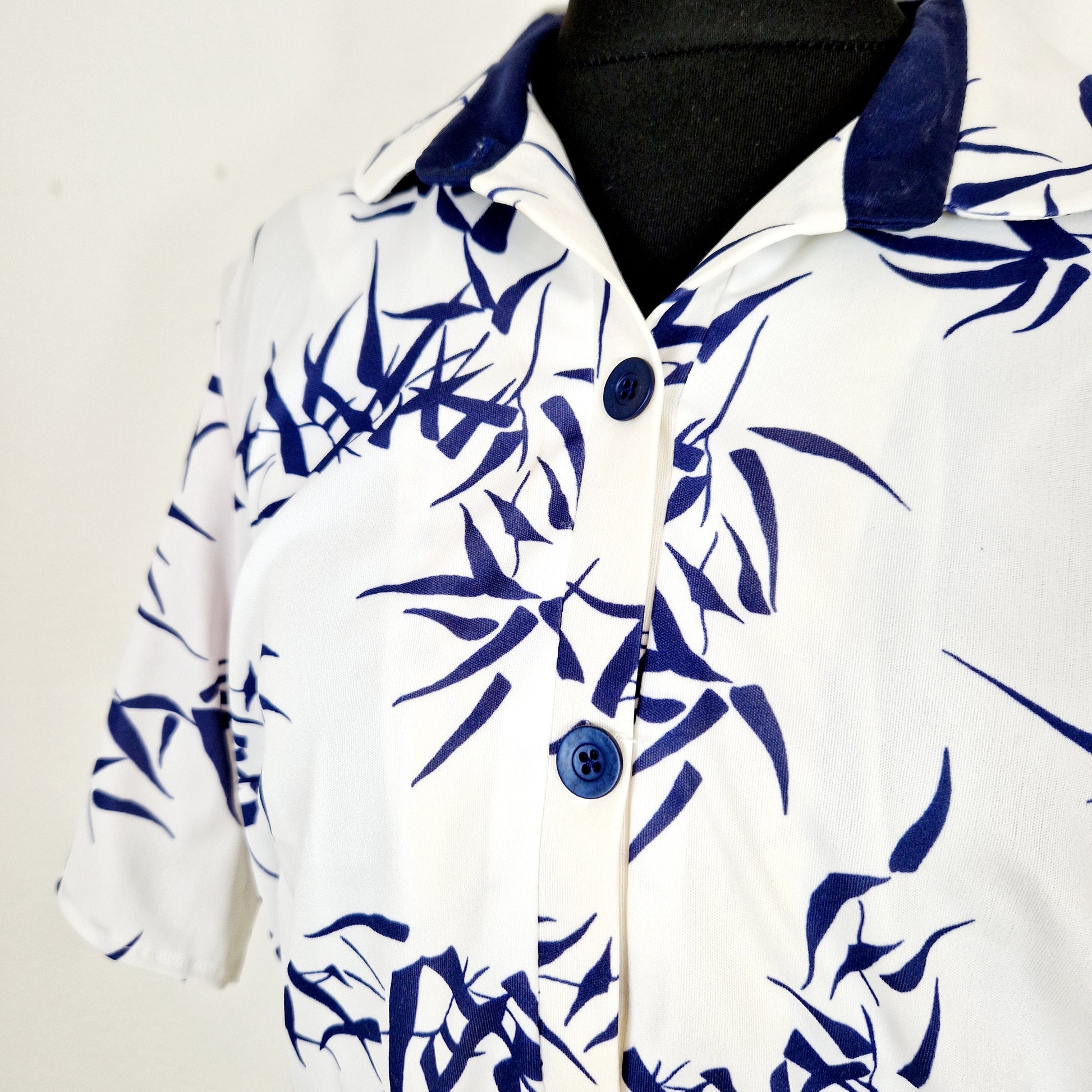 Einzigartiges und nachhaltiges Vintage Kleid in weiss mit blauen Blättern. Unique and sustainable vintage dress in white with blue leaves. Close-up.