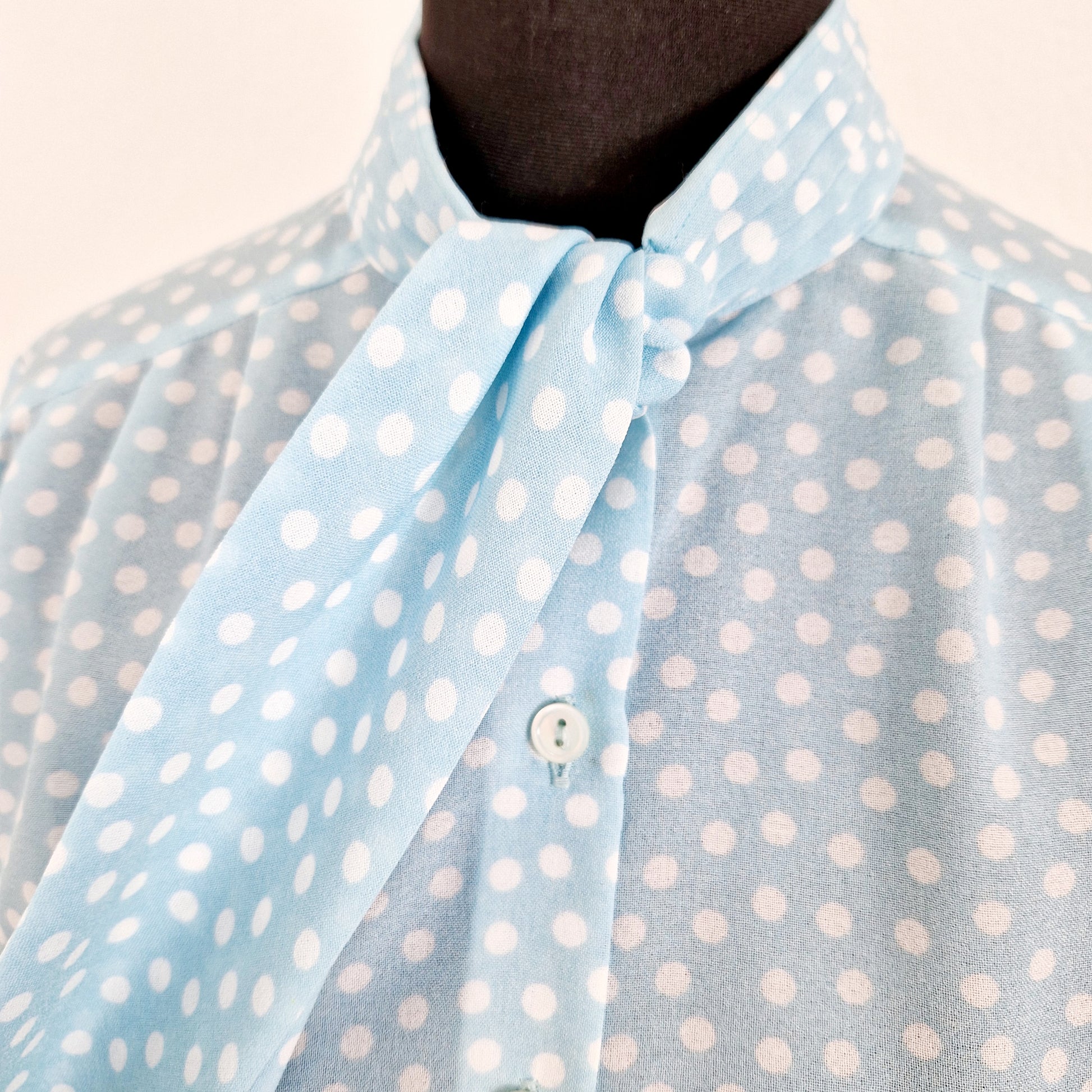 Einzigartige und nachhaltige Vintage Bluse in hellblau mit Punkten. Unique and sustainable vintage blouse in light blue with polka dots. Close-up.