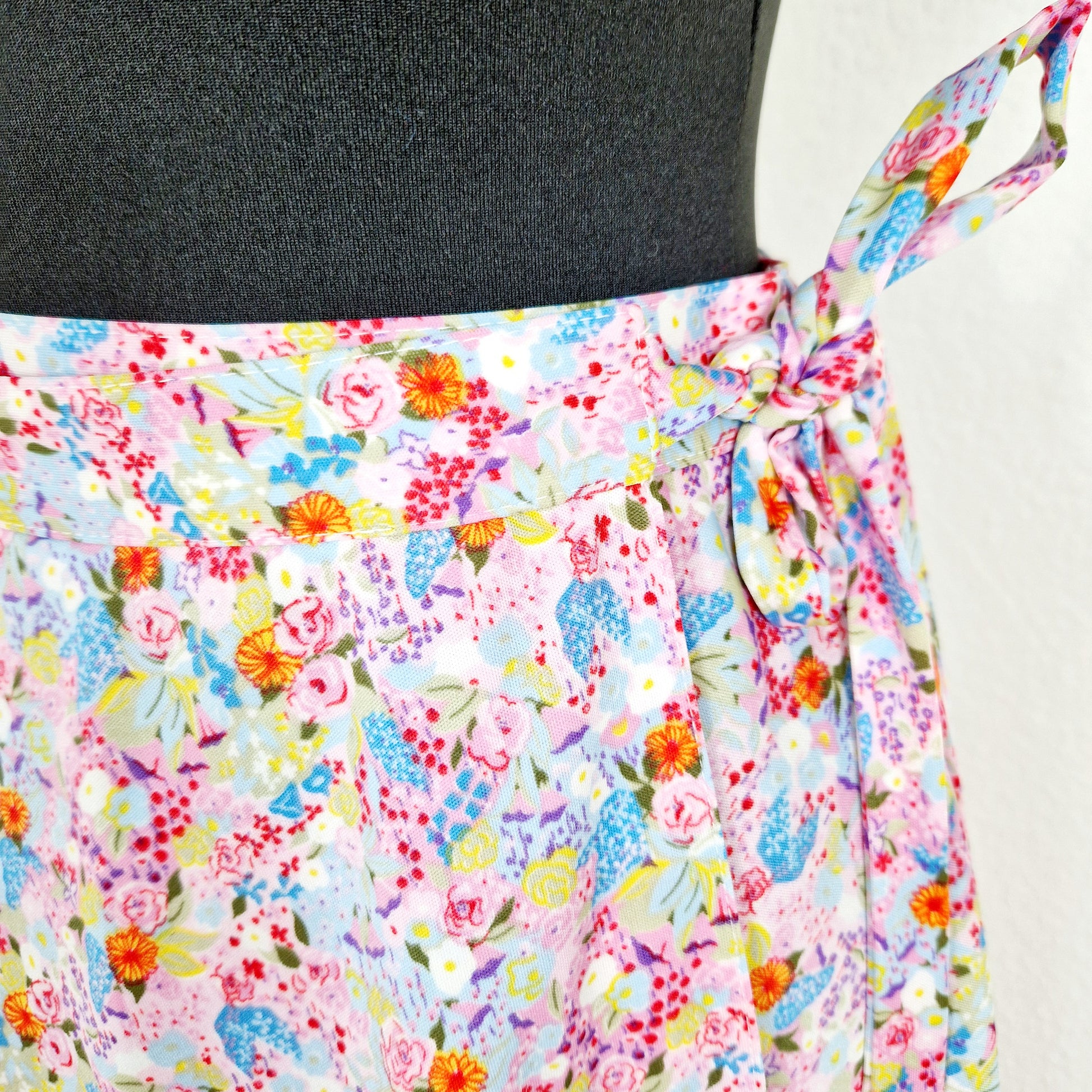 Einzigartiger und nachhaltiger Vintage Wickelrock in rosa-hellblau-hellgrün mit Blumen. Unique and sustainable vintage wrap skirt in pink-light blue-light green with flowers. Close-up.