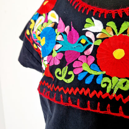 Einzigartiges und nachhaltiges Vintage Kleid in schwarz mit bunten Stickereien. Unique and sustainable vintage dress in black with colorful embroidery. Close-up.