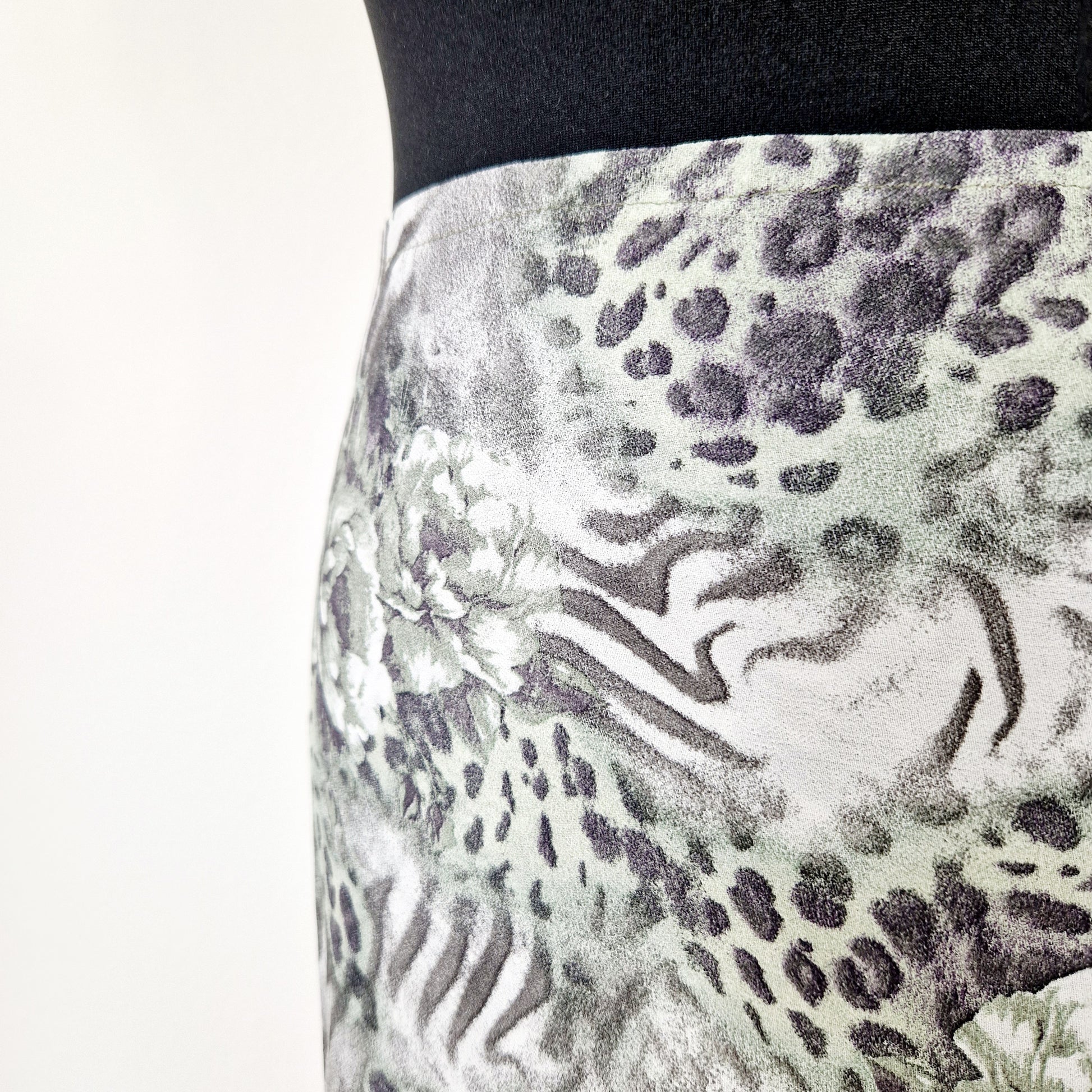 Einzigartiger und nachhaltiger Vintage Wickelrock in grün-grau mit Blumen und Leo-Print. Unique and sustainable vintage wprap skirt in green-grey with flowers and leo print. Close-up.