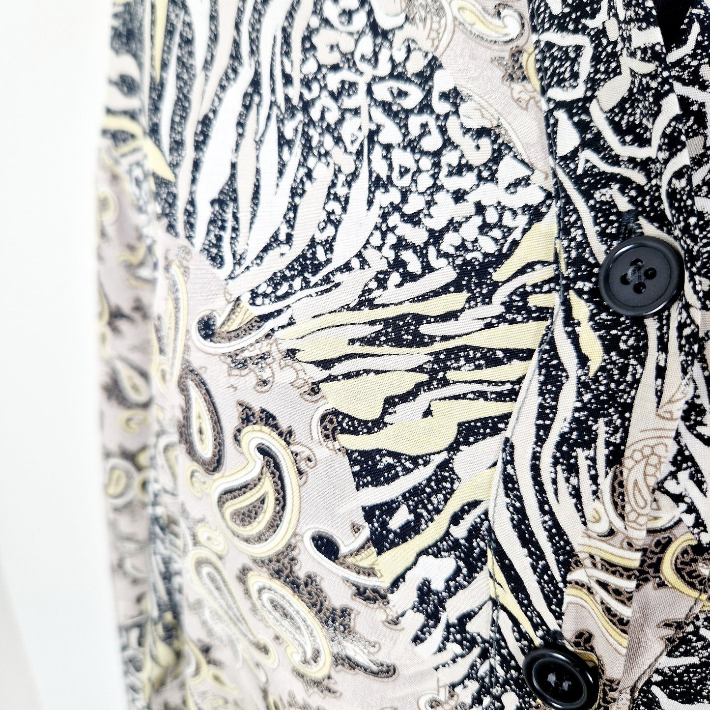 Einzigartige und nachhaltige Vintage Bluse in beige-gelb-schwarz mit Paisley und Leo. Unique and sustainable vintage blouse in beige-yellow-black with paisley and leo. Close-up.