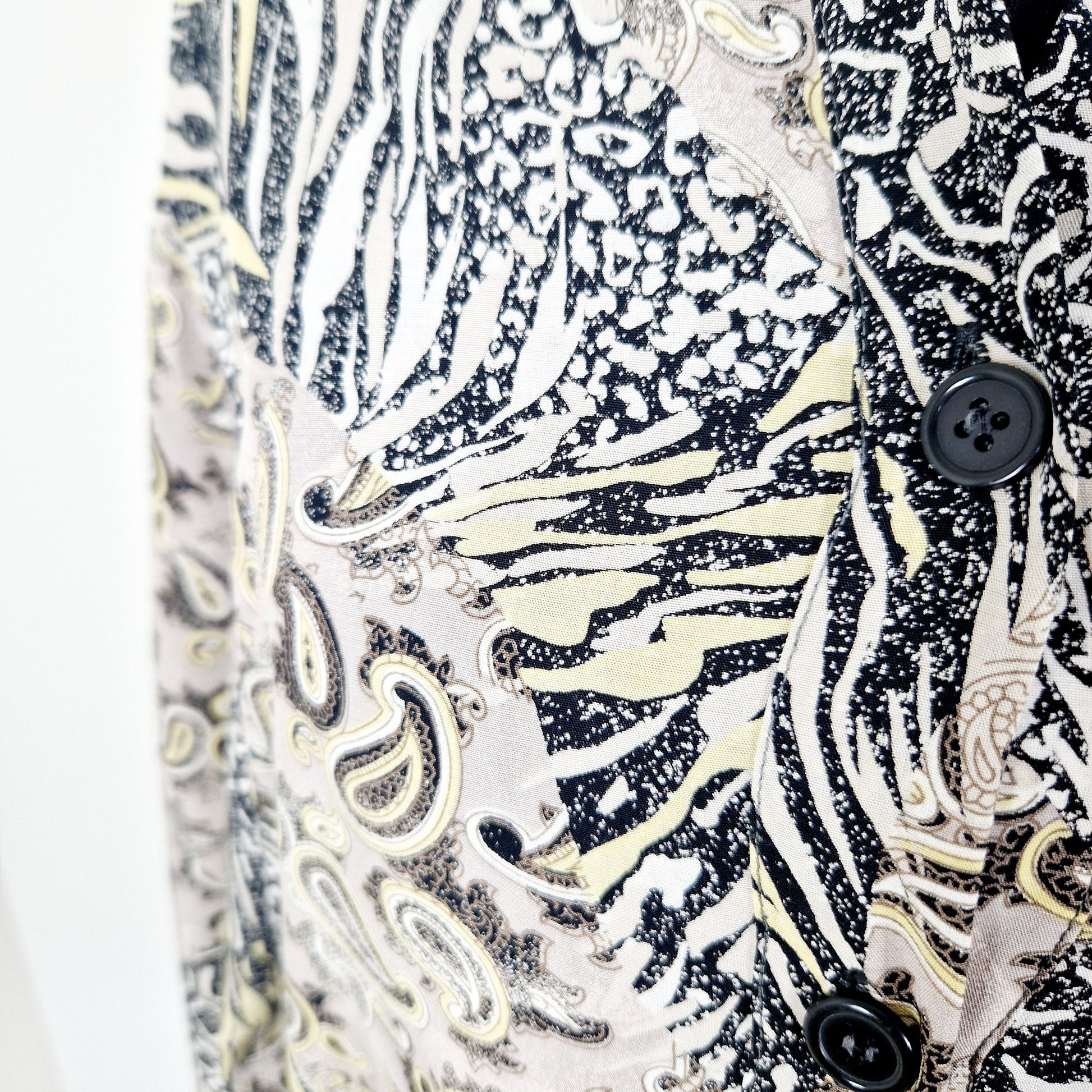 Einzigartige und nachhaltige Vintage Bluse in beige-gelb-schwarz mit Paisley und Leo. Unique and sustainable vintage blouse in beige-yellow-black with paisley and leo. Close-up.