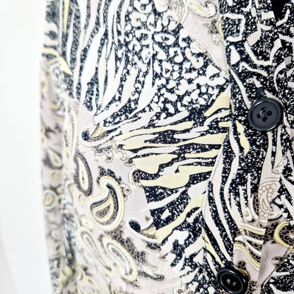 Einzigartige und nachhaltige Vintage Bluse in beige-gelb-schwarz mit Paisley und Leo. Unique and sustainable vintage blouse in beige-yellow-black with paisley and leo. Close-up.
