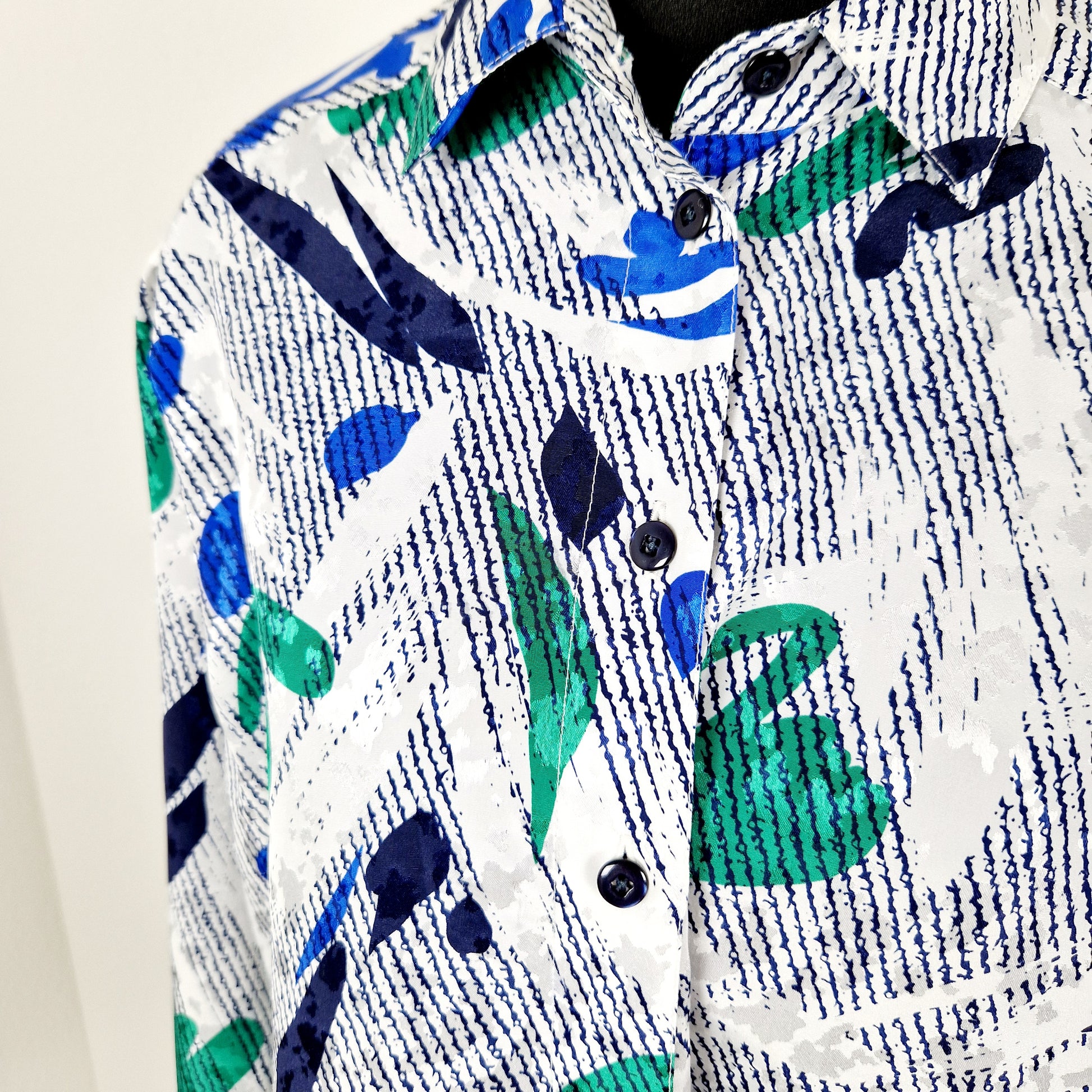 Einzigartige und nachhaltige Vintage Bluse in weiss-blau-grün. Unique and sustainable vintage blouse in white-dark blue-green. Close-up.