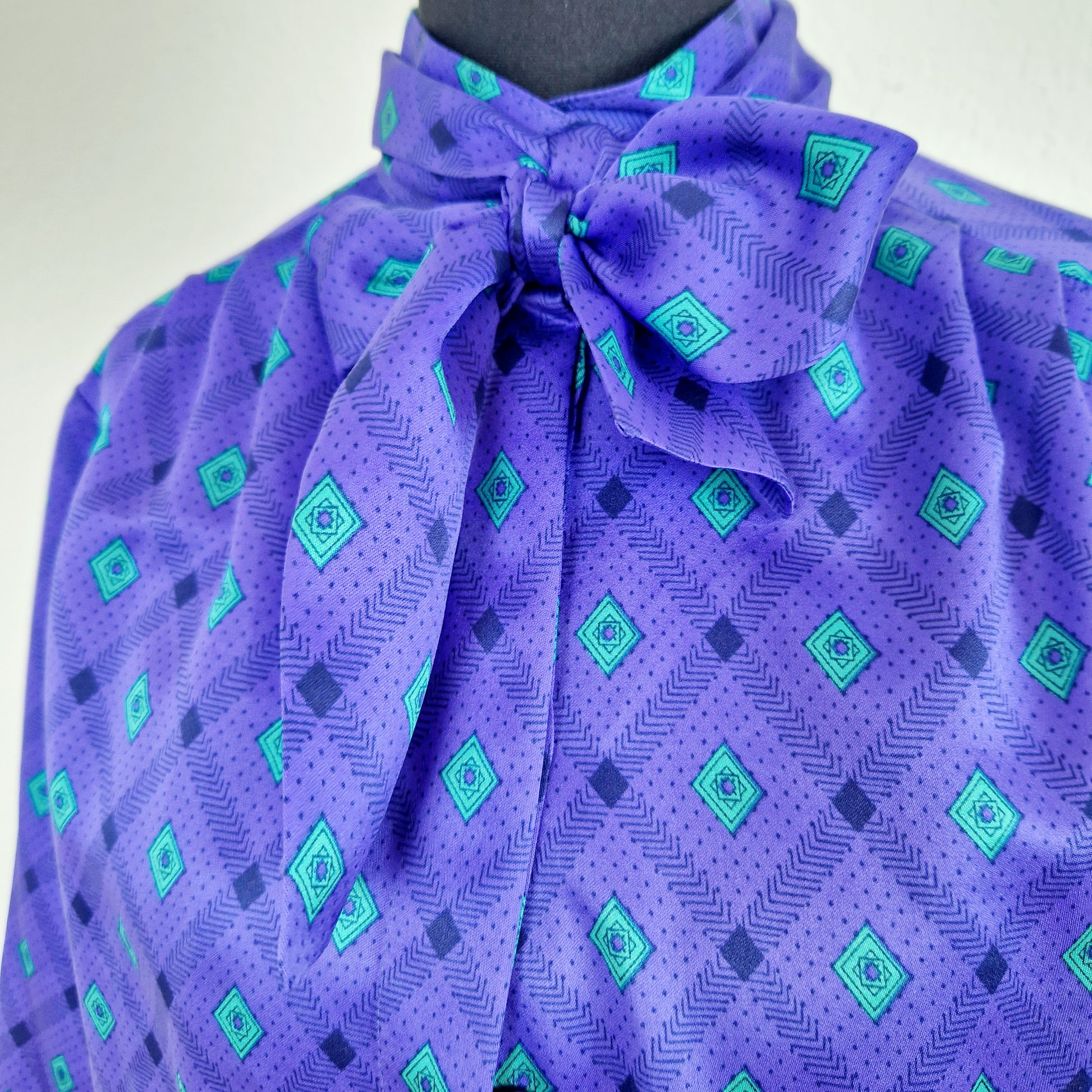 Einzigartige und nachhaltige Vintage Bluse in violett-grün mit Rauten. Unique and sustainable vintage blouse in purple-green with rhombs. Close-up.