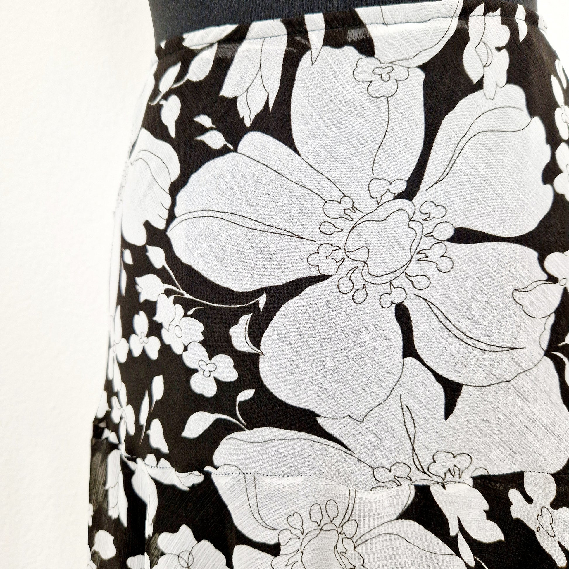 Einzigartiger und nachhaltiger Vintage Rock in schwarz-weiss mit Blumen. Unique and sustainable vintage skirt in black and white with flowers. Close-up.