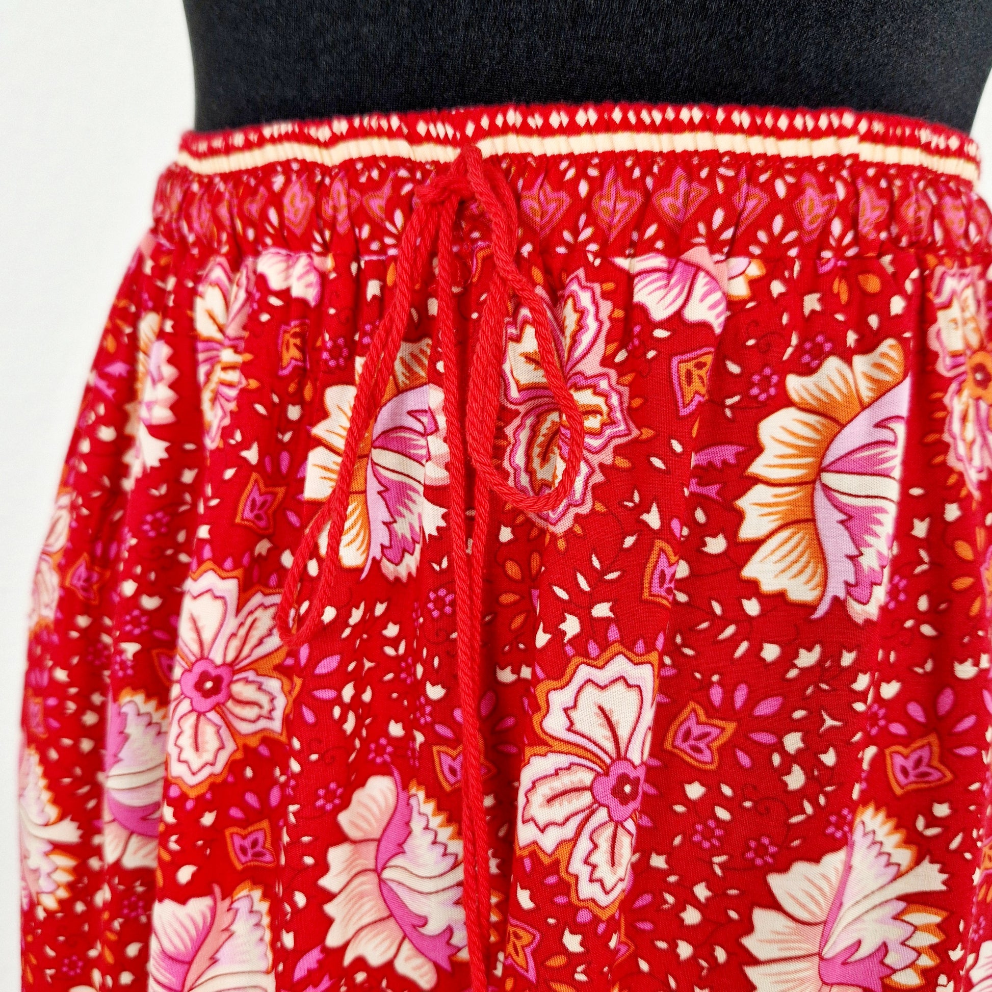 Einzigartiger und nachhaltiger Vintage Rock in rot-pink-gelb mit Blumen und Jaguar. Unique and sustainable vintage skirt in red-pink-yellow with flowers and jaguar. Close-up.