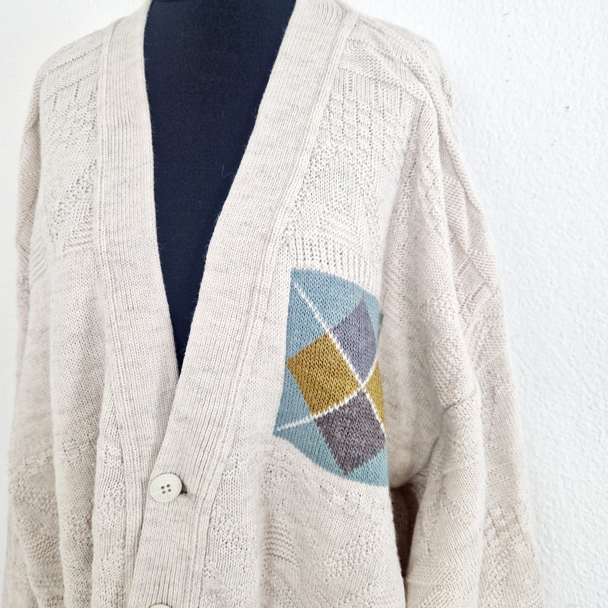 Einzigartiger und nachhaltiger Vintage Cardigans in creme mit geometrischem Muster. Unique and sustainable vintage cardigan in creme with geometric pattern. Close-up.