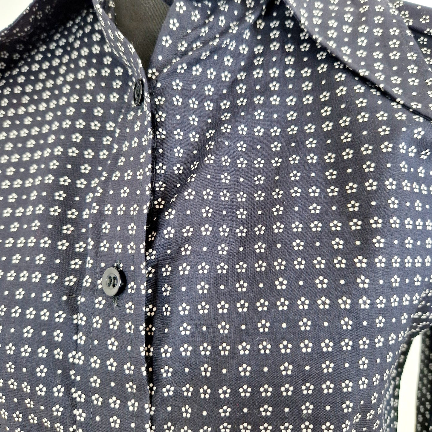 Einzigartige und nachhaltige  Vintage Bluse in dunkelblau mit weissen Blumen. Unique and sustainable vintage blouse in dark blue with white flowers. Close-up.