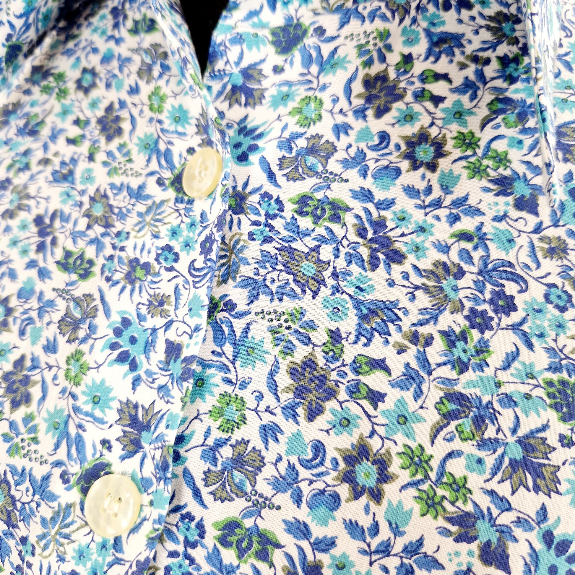 Einzigartige und nachhaltige Vintage Bluse in blau-türkis-weiss mit Blumen. Unique and sustainable vintage blouse in blue-turquoise-white with flowers. Close-up.