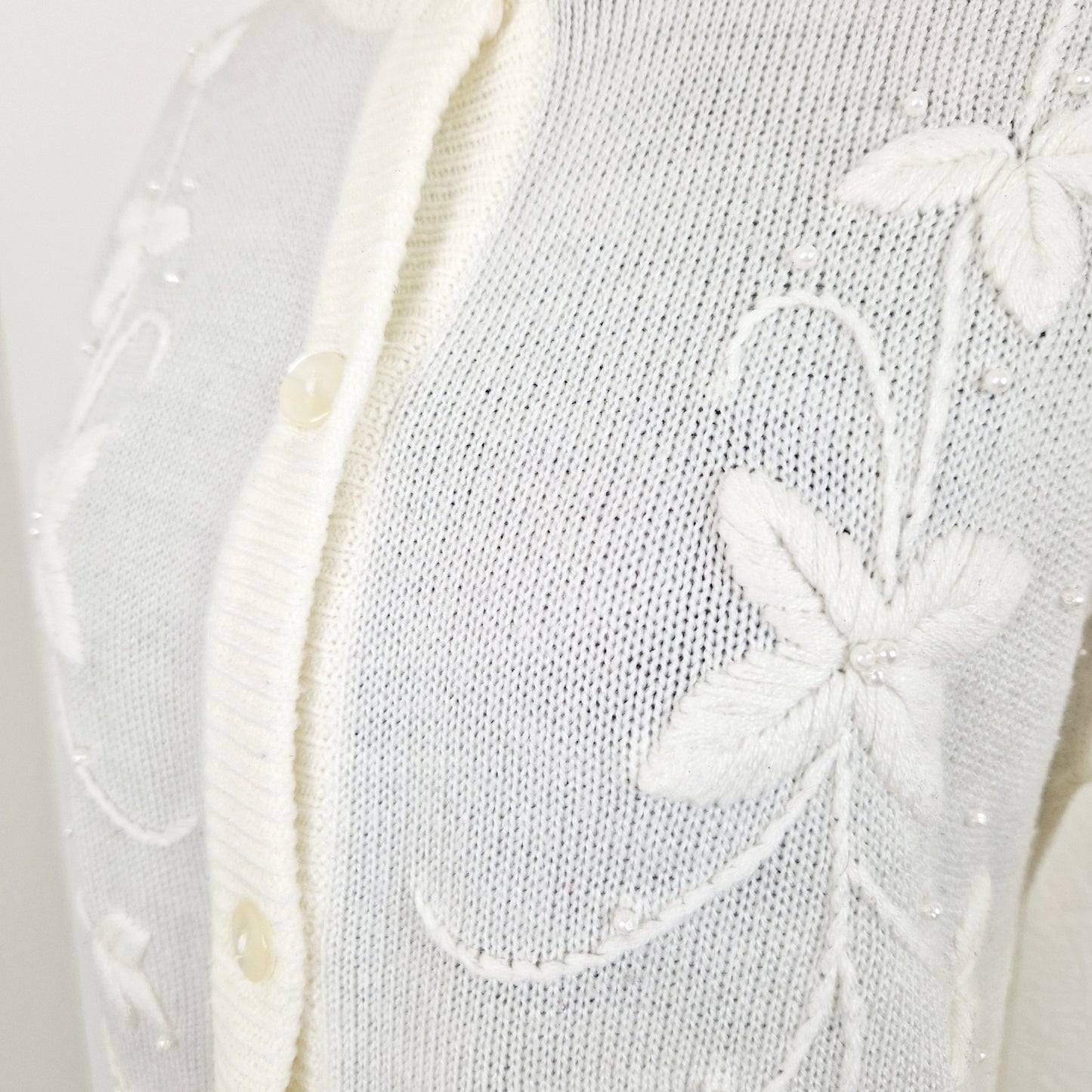 Einzigartiger und nachhaltiger Vintage Cardigan in Eierschale mit Blumenstickereien und Perlen. Unique and sustainable vintage cardigan in off-white with flower embroidery and pearls. Close-up.