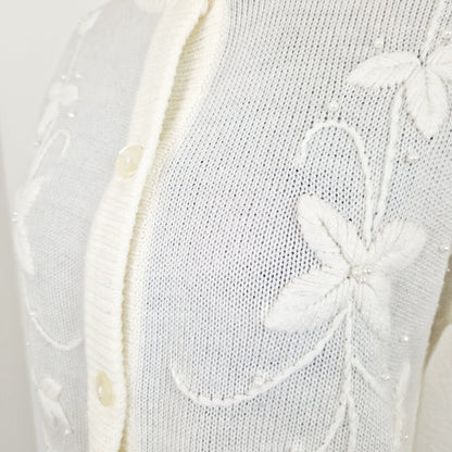 Einzigartiger und nachhaltiger Vintage Cardigan in Eierschale mit Blumenstickereien und Perlen. Unique and sustainable vintage cardigan in off-white with flower embroidery and pearls. Close-up.