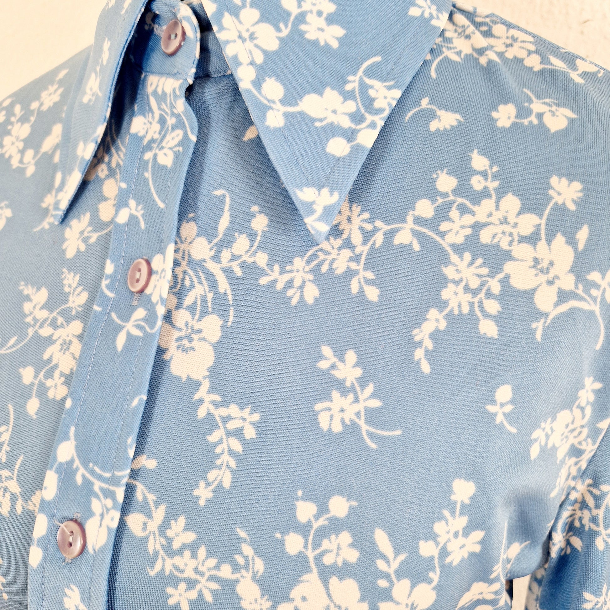 Einzigartige und nachhaltige Vintage Bluse in hellblau mit Blumen. Unique and sustainable vintage blouse in light blue with flowers. Close-up.