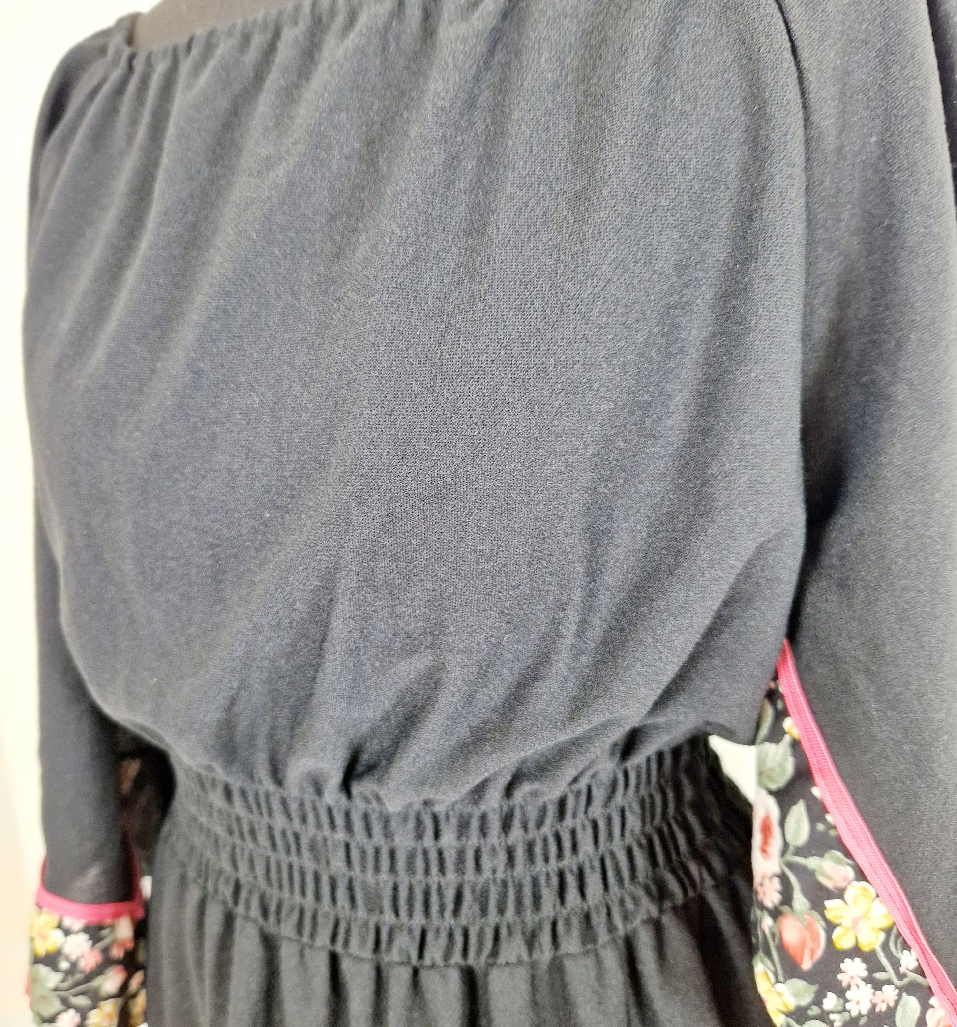 Einzigartiges und nachhaltiges Vintage Kleid in Schwarz mit Blumen und Trompetenärmeln. Unique and sustainable vintage dress in black with flowers and trompet sleeves. Close-up.