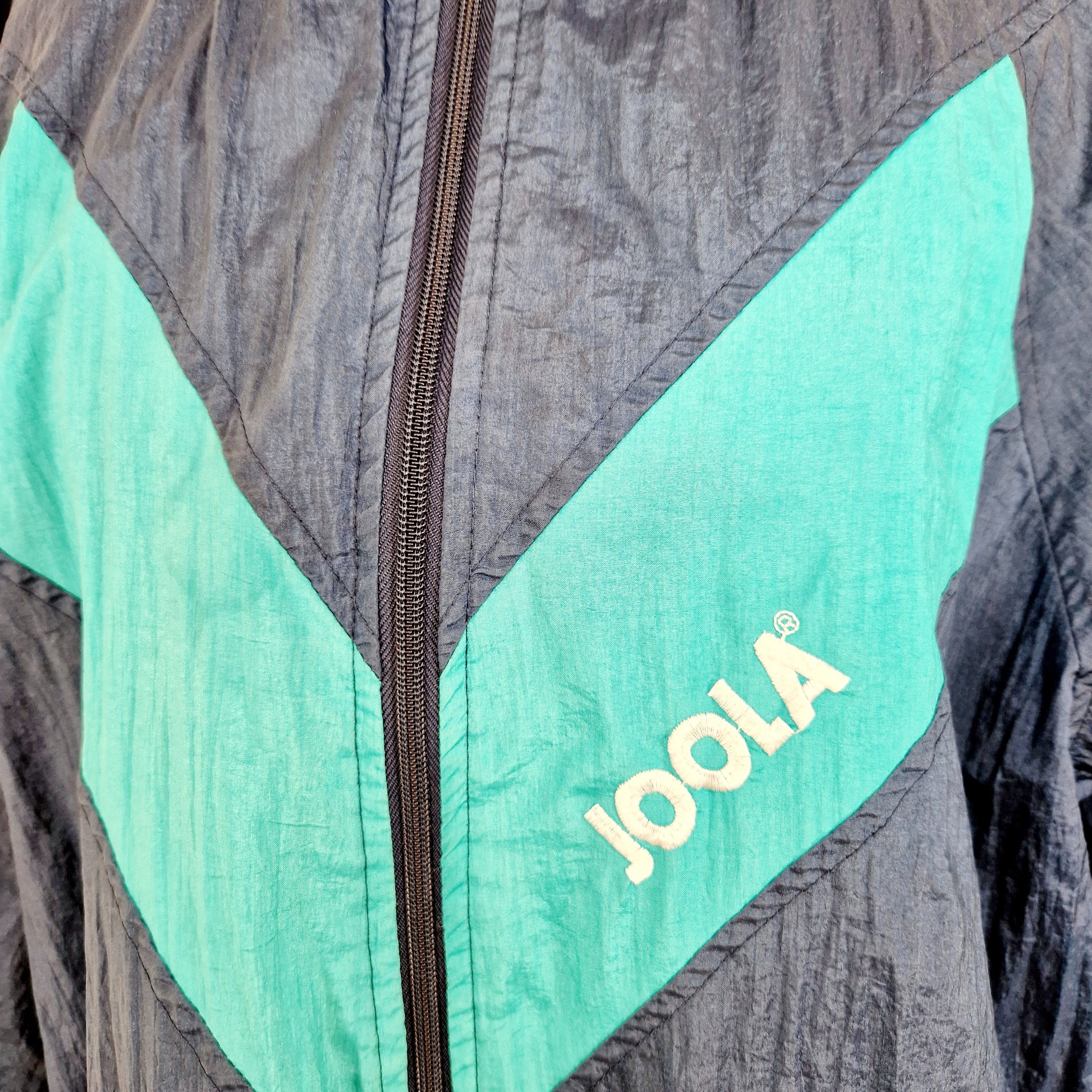 Einzigartige und nachhaltige Vintage Trainerjacke in blau-türkis von Joola. Unique and sustainable vintage track jacket in blue-turquois from Joola. Close-up.