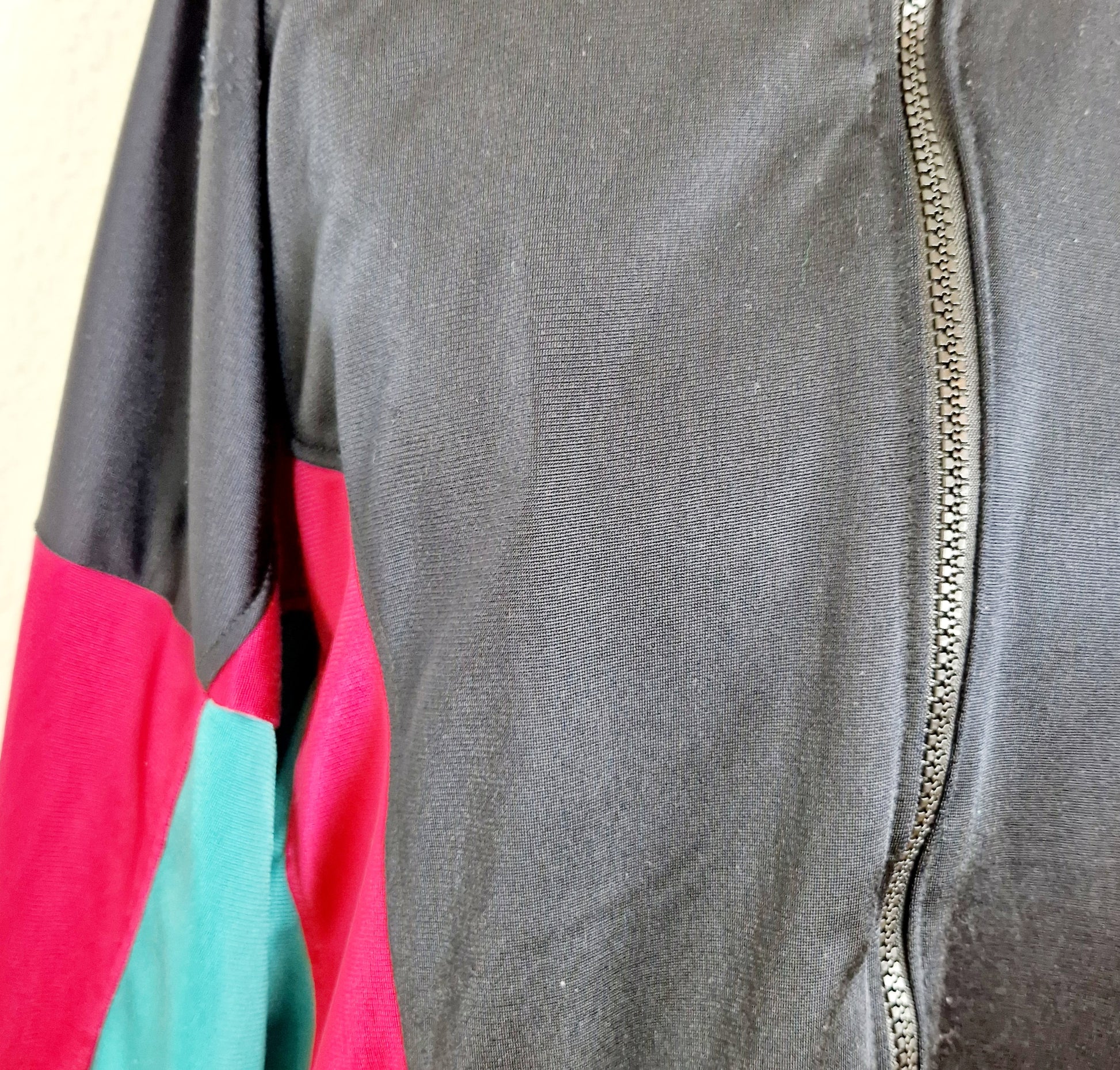Einzigartige und nachhaltige Vintage Trainerjacke in schwarz-rot-grün. Unique and sustainable vintage track jacket in black-red-green. Close-up.