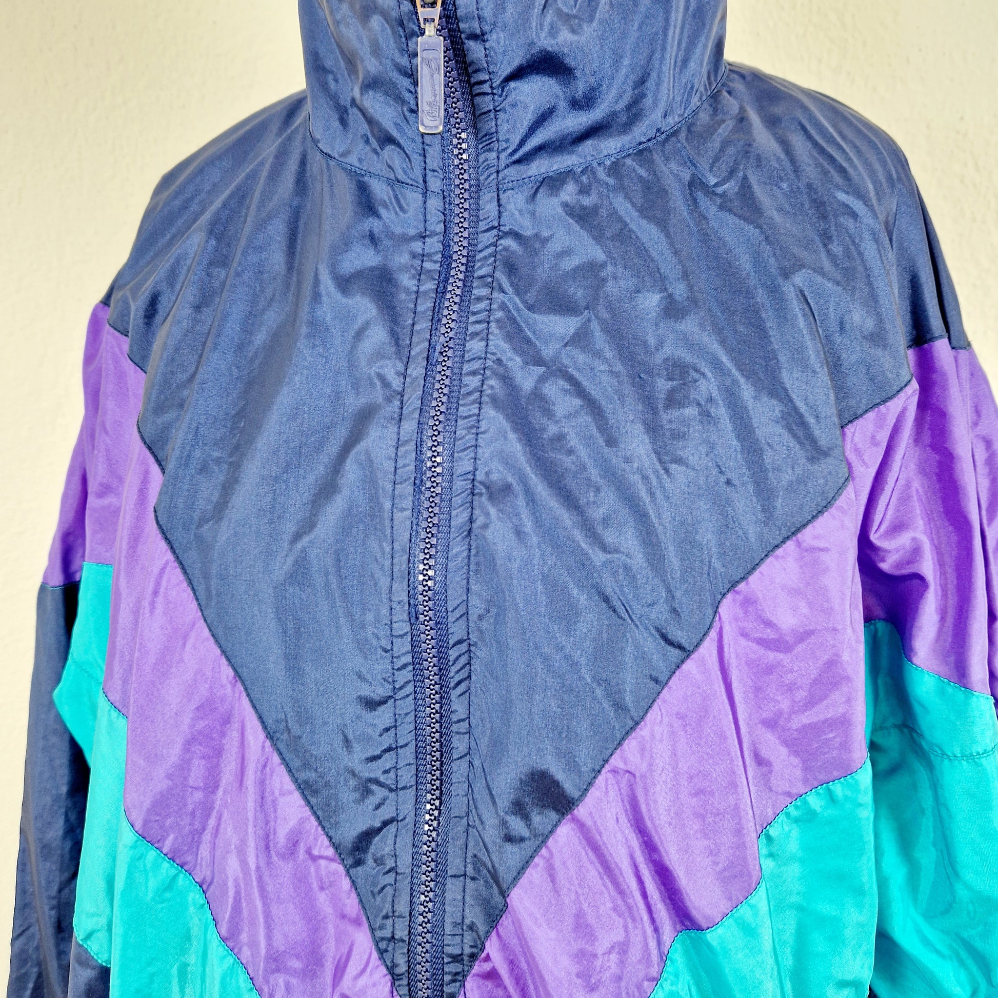 Einzigartige und nachhaltige Vintage Trainerjacke in dunkelblau-türkis-violett. Unique and sustainable vintage track jacket in dark blue-turquois-purple. Close-up.
