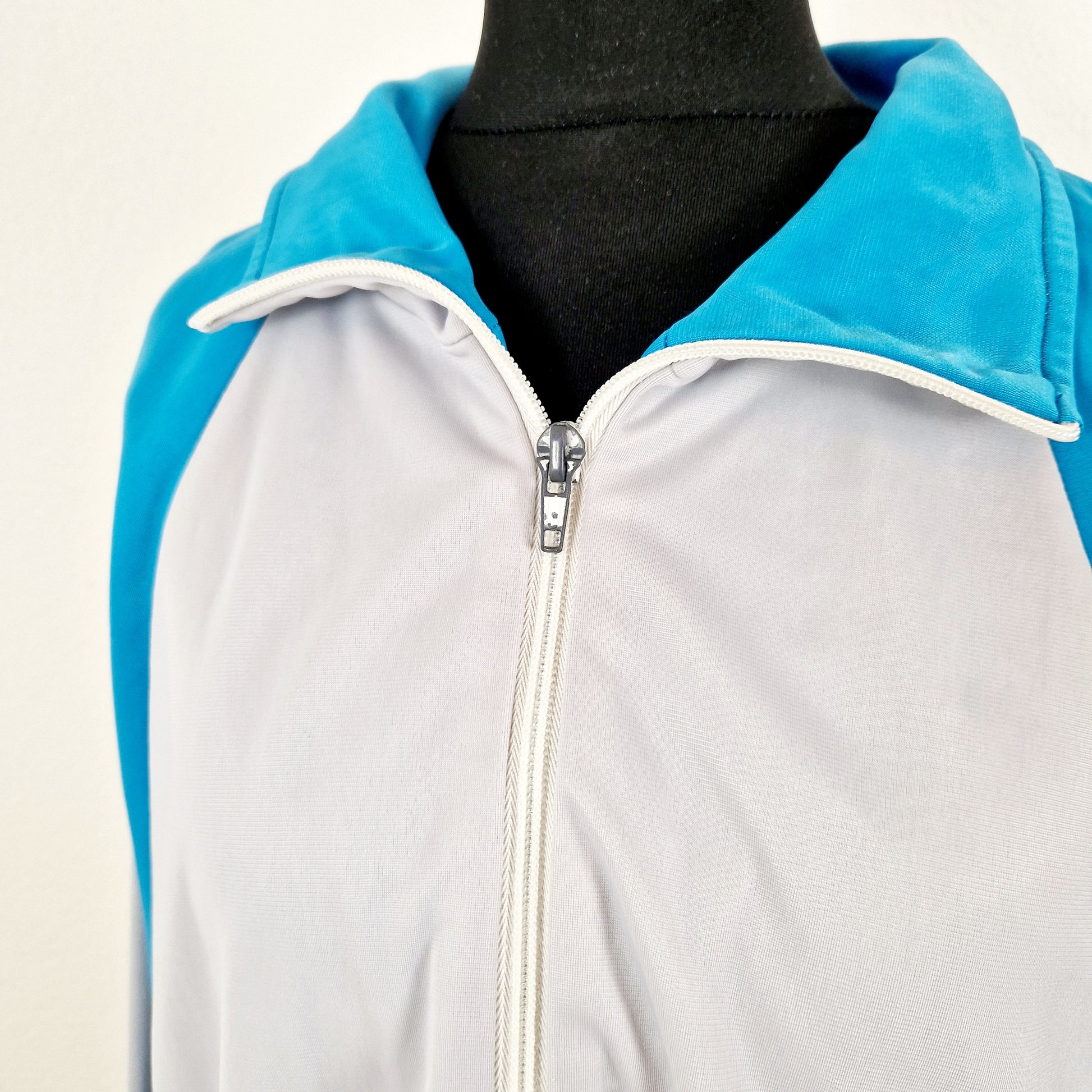 Einzigartige und nachhaltige Vintage Trainerjacke in hellgrau-türkis. Unique and sustainable vintage track jacket in light grey-turquois. Close-up.