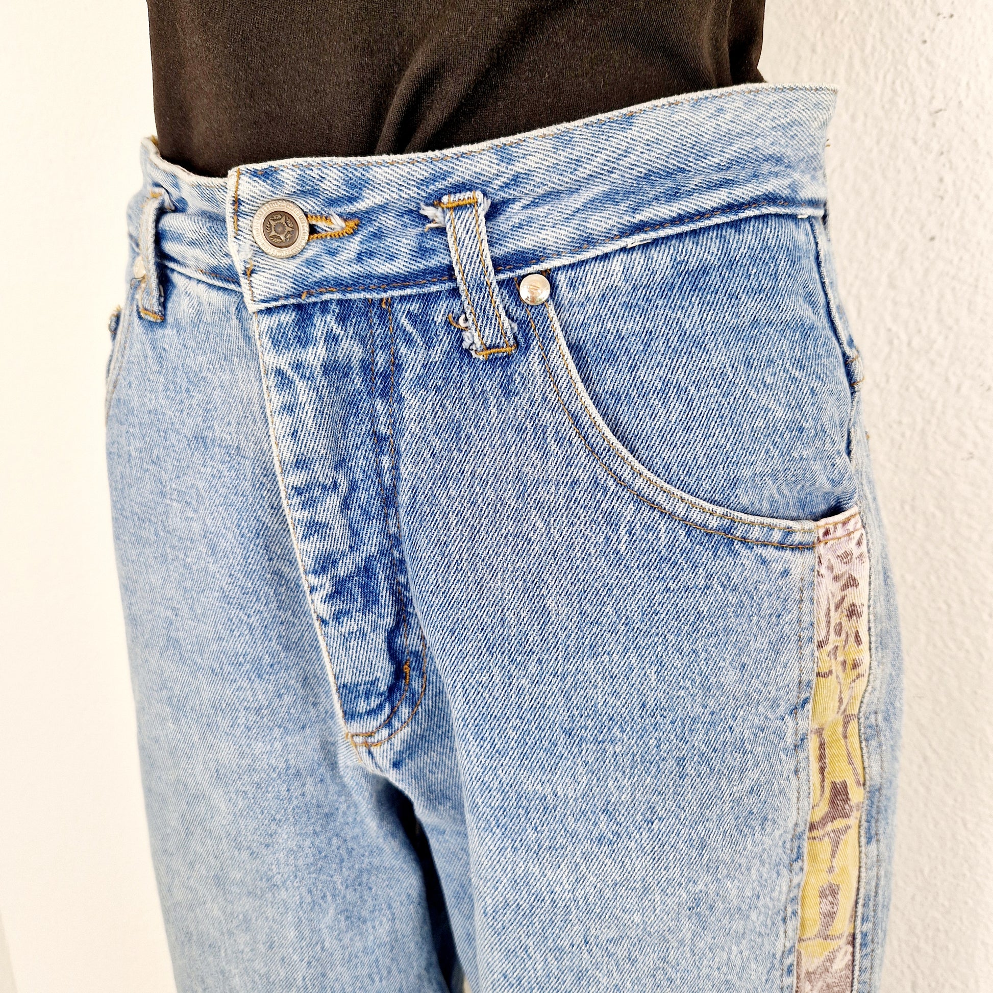 Einzigartige und nachhaltige Vintage Jeans in mittelblau-beige-violett, mit Streifen. Close-up.