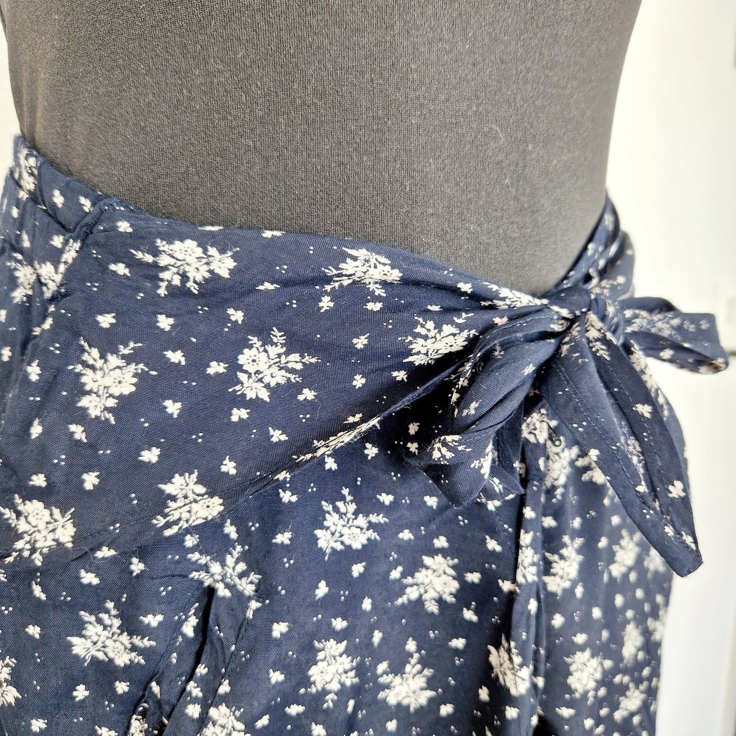 Einzigartige und nachhaltige Vintage Hose in dunkelblau-weiss mit Blumen und Gürtel. Unique and sustainable vintage pants in dark blue-white with flowers and belt. Close-up.