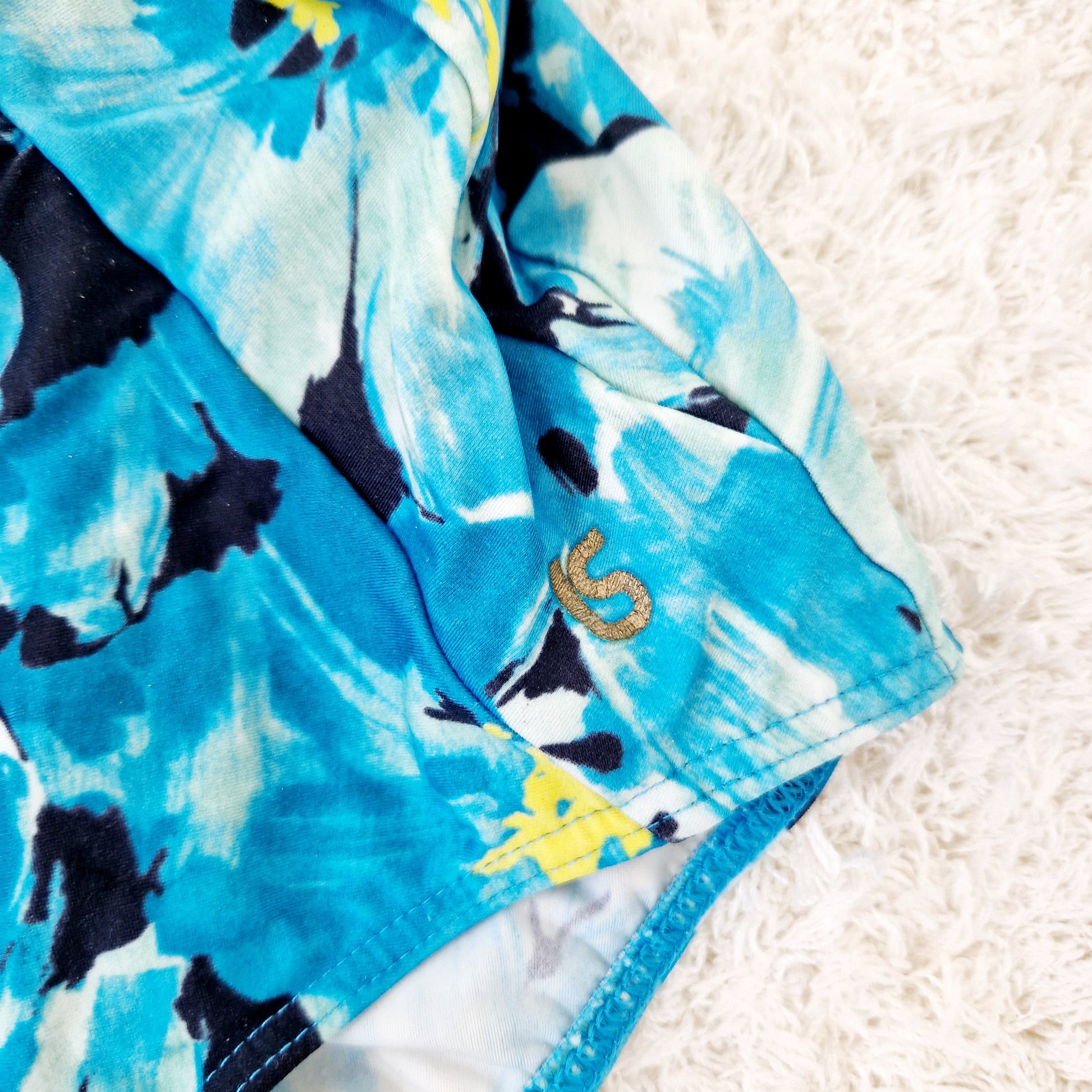 Einzigartiger und nachhaltiger Vintage Badeanzug in blau-gelb-mint mit Blumen. Unique and sustainable vintage swimsuit in blue-yellow-mint with flowers. Close-up.