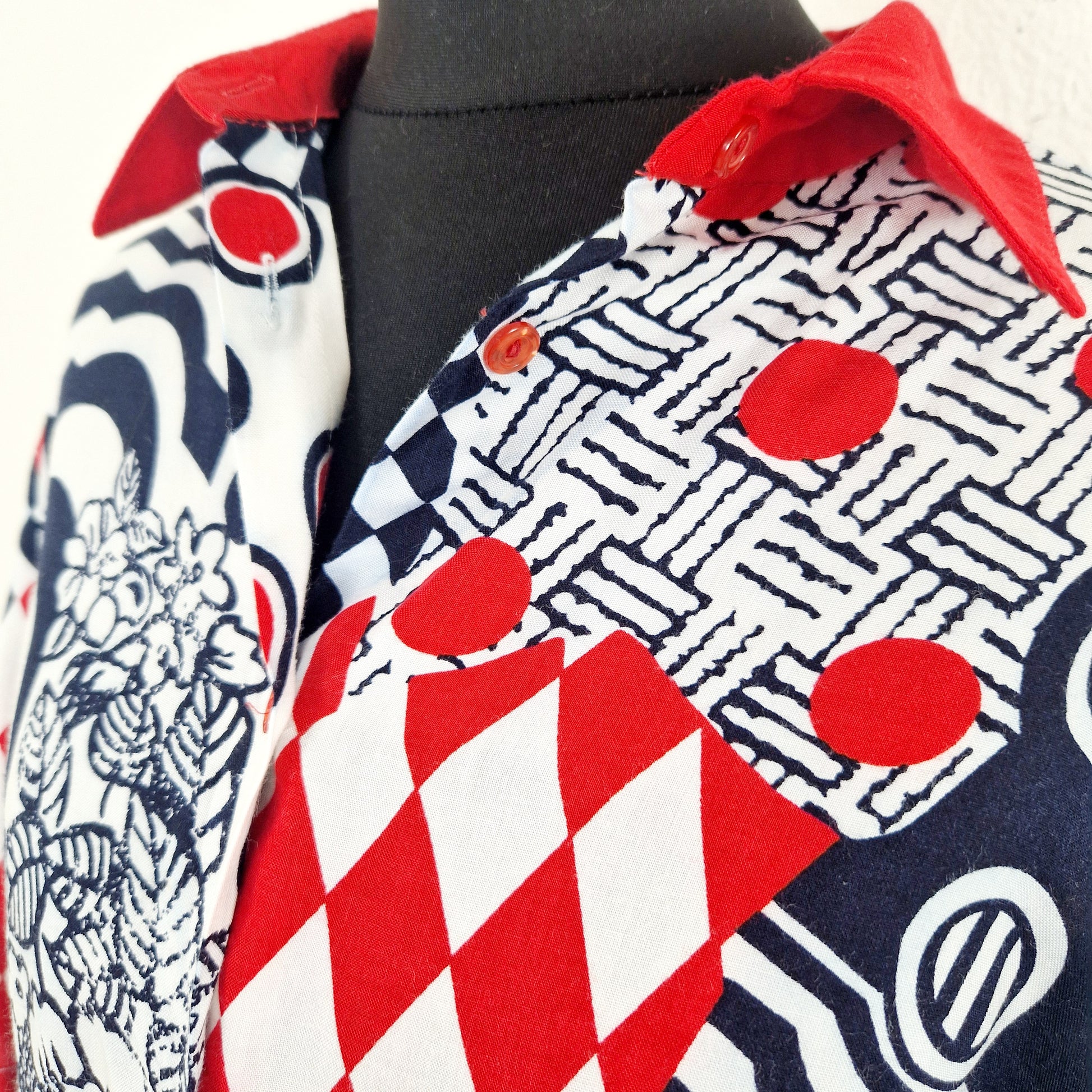 Einzigartige und nachhaltige Vintage Bluse, Kurzarm, in weiss-rot-blau, geometrisch. Unique and sustainable vintgage blouse, short sleeved, in white-red-blue, geometric. Close-up.