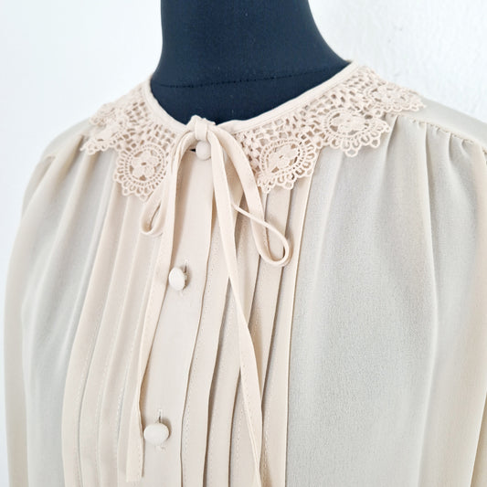 Einzigartige und nachhaltige Vintage Bluse in hellbeige mit Schleife und Häkelkragen. Unique and sustainable vintage blouse in light beige with bow an crocheted collar. Close-up.