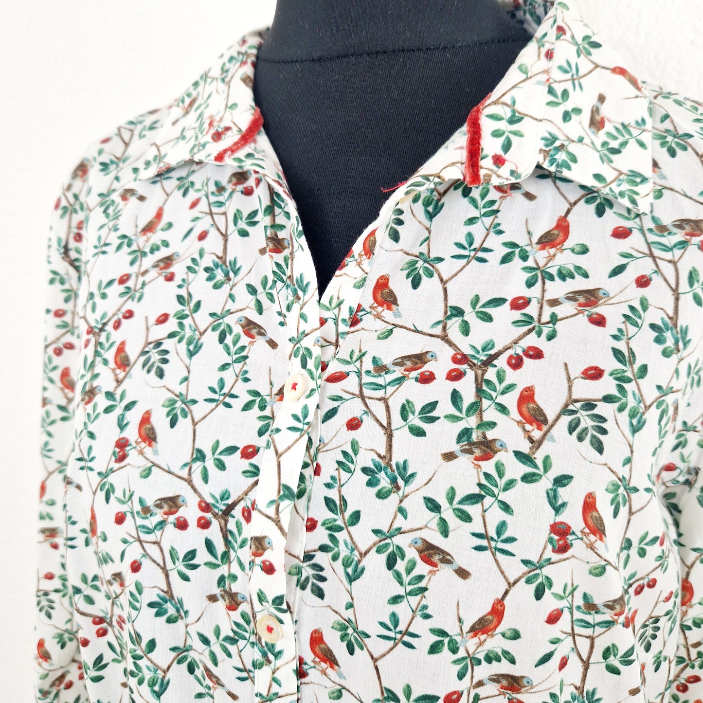 Einzigartige und nachhaltige Vintage Bluse in weiss-grün-rot mit  Vögeln. Unique and sustainable vintage blouse in white-green-red with birds. Close-up.
