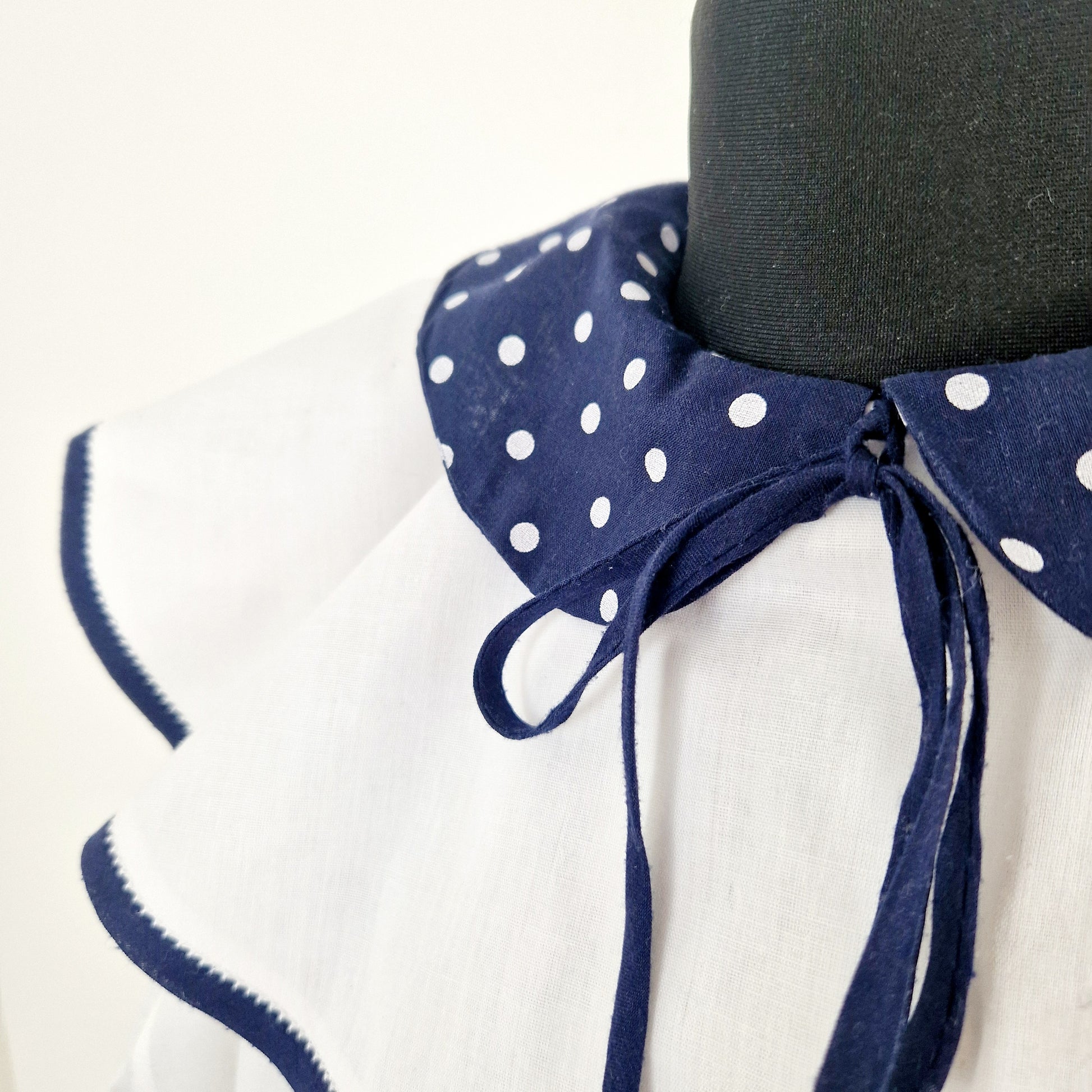 Einzigartige und nachhaltige Vintage Bluse in weiss-blau mit Kragen und Schleife. Unique and sustainable vintage blouse in white-blue with collar and bow. Close-up.