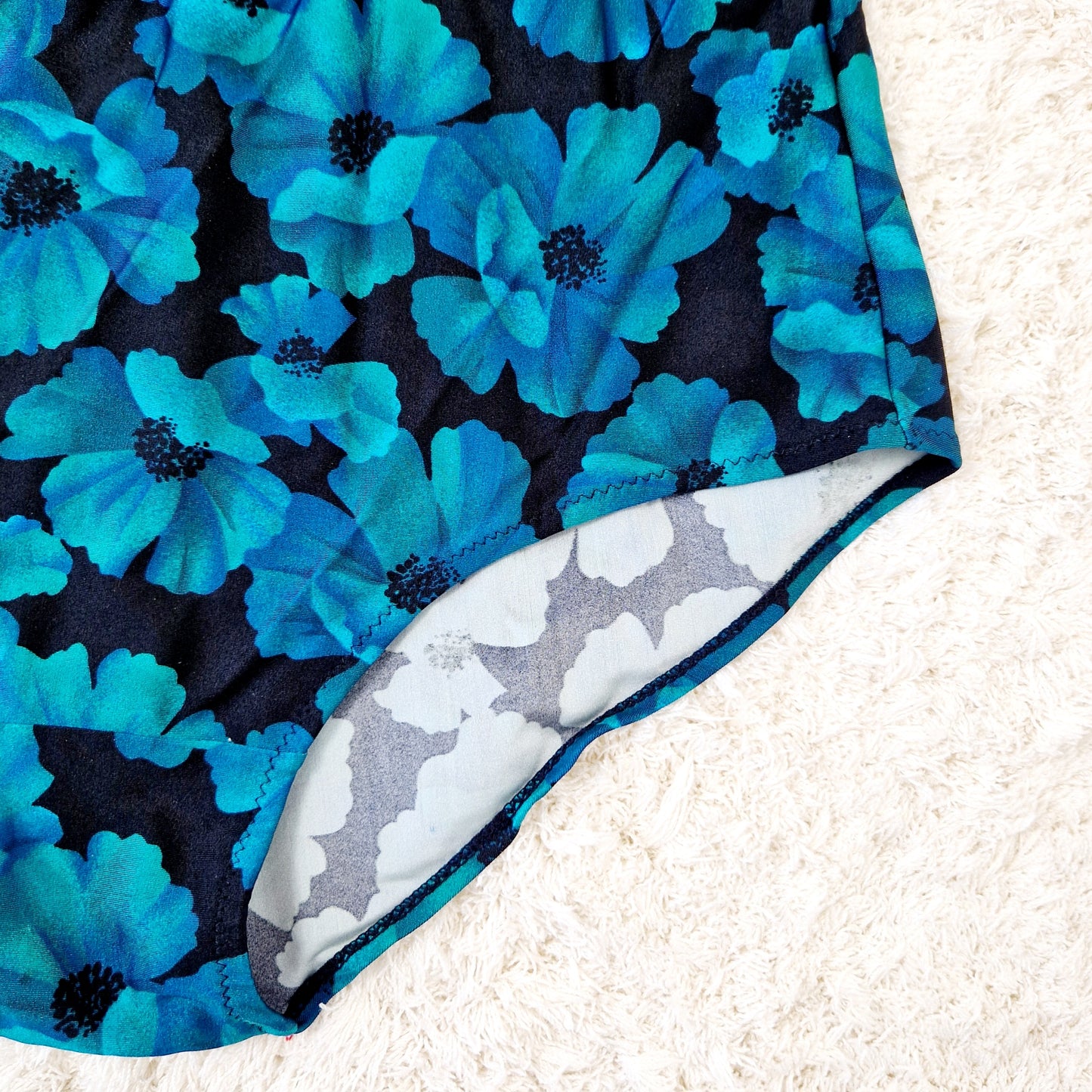 Einzigartiger und nachhaltiger Vintage Badeanzug in petrol-schwarz mit Blumen. Unique and sustainable vintage swimsuit in petrol-black with flowers. Close-up.
