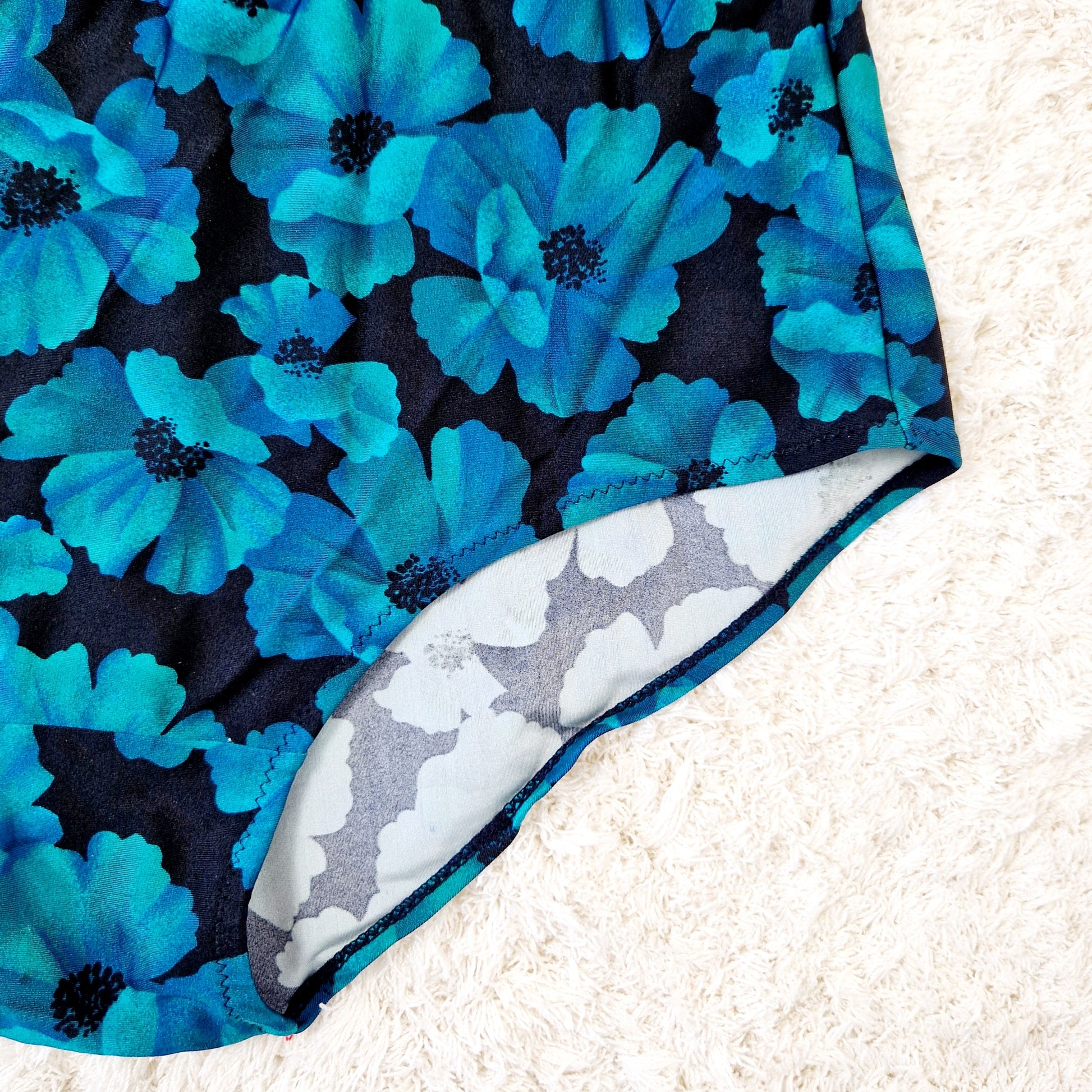 Einzigartiger und nachhaltiger Vintage Badeanzug in petrol-schwarz mit Blumen. Unique and sustainable vintage swimsuit in petrol-black with flowers. Close-up.