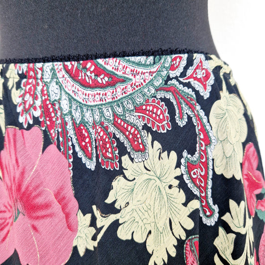 Einzigartiger und nachhaltiger Vintage Rock in schwarz-pink-gelb mit Blumen und Paisley. Unique and sustainable vintage skirt in black-pink-yellow with flowers and paisley. Close-up.