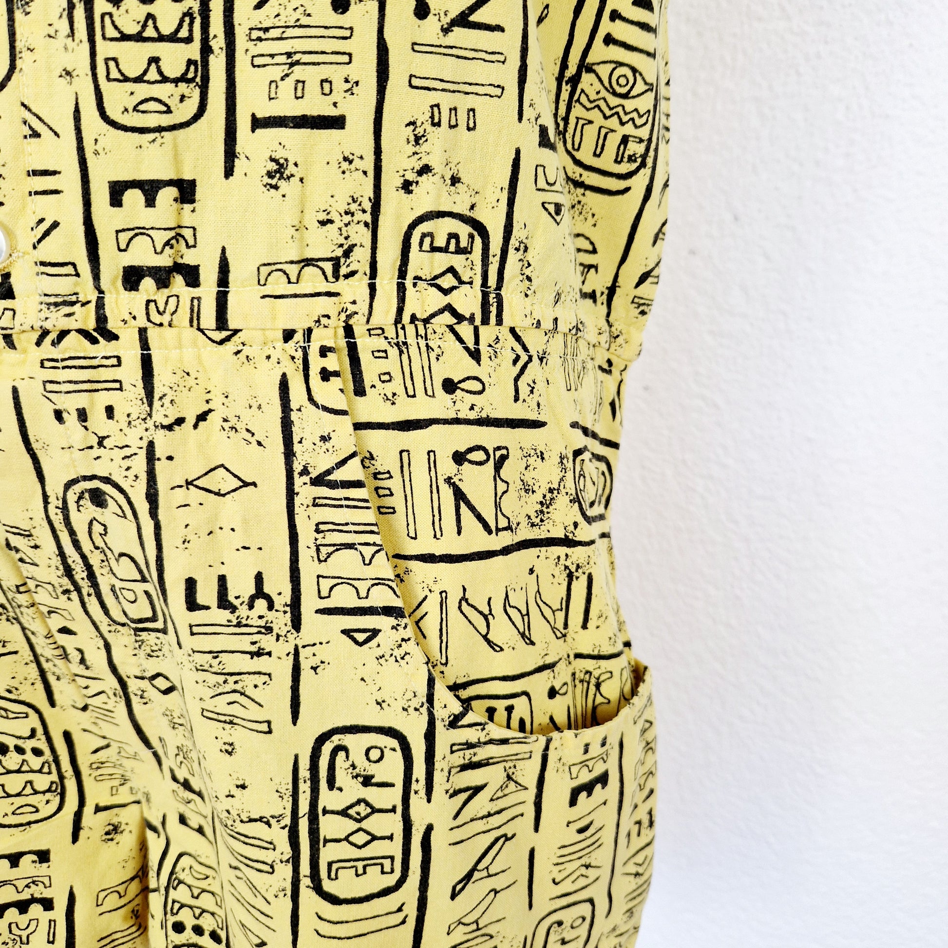 Einzigartiger und nachhaltiger Vintage Playsuit in gelb-schwarz mit Hieroglyphen. Unique and sustainable vintage playsuit in yellow-black with hieroglyphics. Close-up.