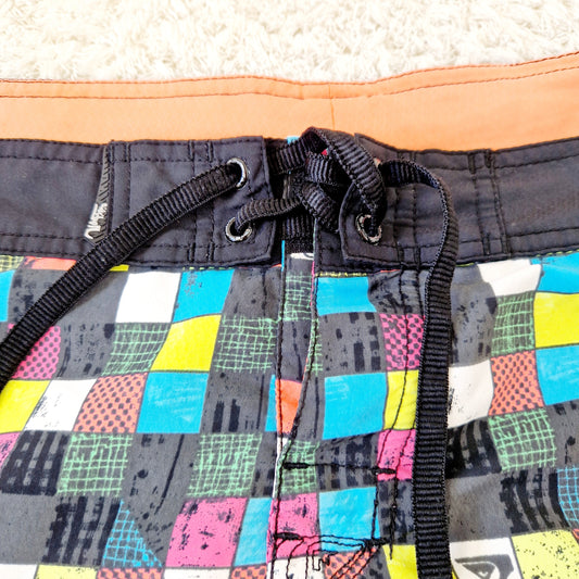 Einzigartige und nachhaltige Vintage Badeshorts in schwarz-orange-türkis von Quicksilver. Unique and sustainable vintage Swimtrunks in black-orange-turquois from Quicksilver. Close-up.