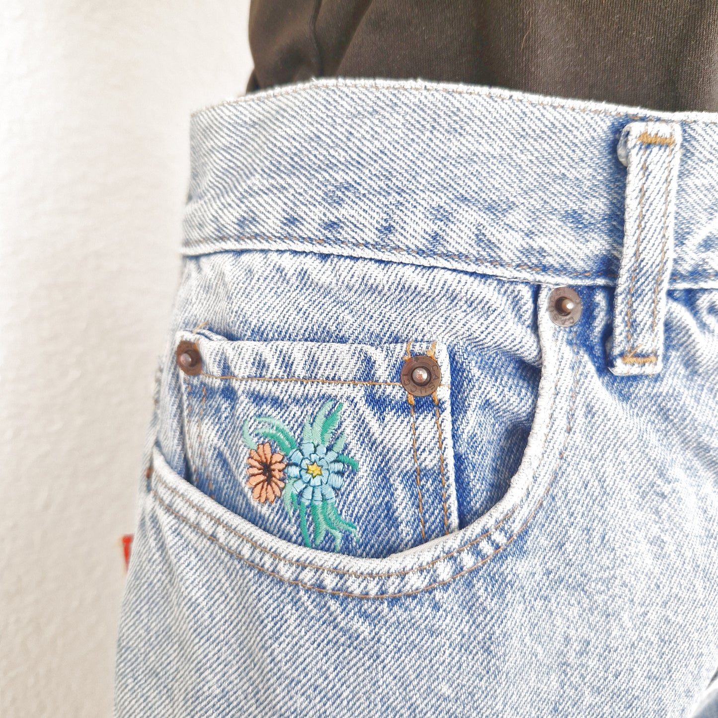 Einzigartige und nachhaltige Vintage Jeans, mittelblau, mit Blumenstickereien. Close-up.