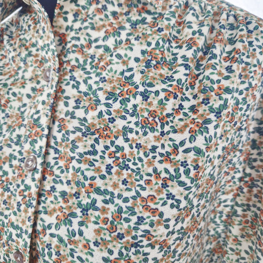 Einzigartige und nachhaltige Vintage Bluse in beige-grün-orange mit Blumen. Close-up.