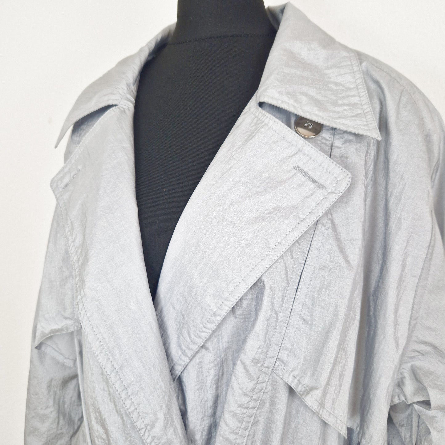 Einzigartiger und nachhaltiger Vintage Regenmantel in hellgrau. Unique and sustainable vintage raincoat in light grey. Close-up.